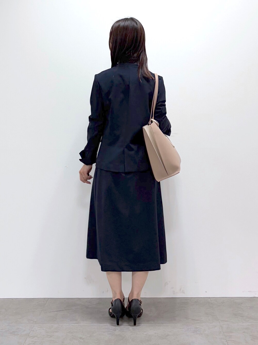 ブラック系のパンプス、ベージュ系のトートバッグ、ブルー系のスカートを着用したレディースの春コーディネートの3枚目の写真