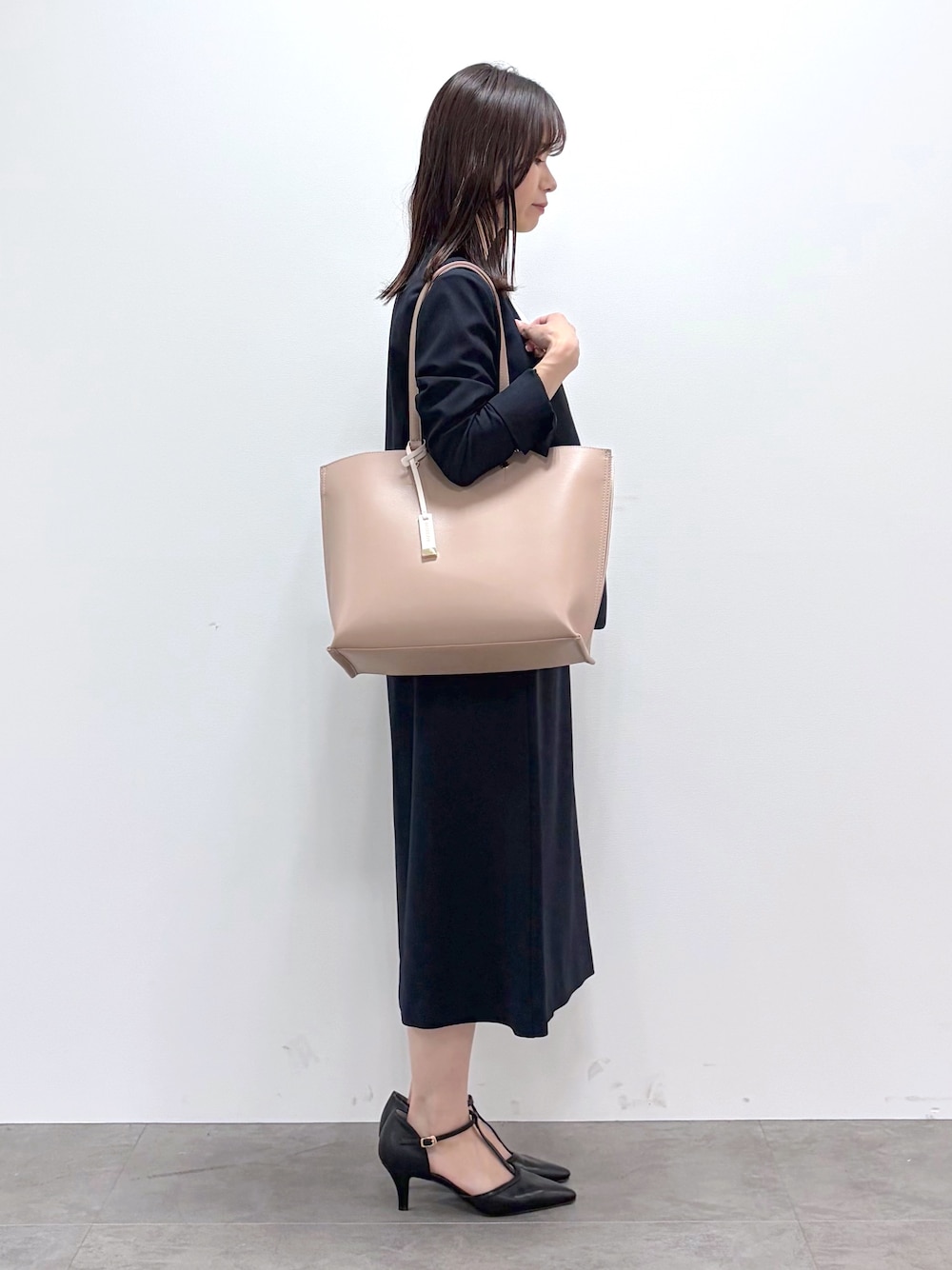 ブラック系のパンプス、ベージュ系のトートバッグ、ブルー系のスカートを着用したレディースの春コーディネートの2枚目の写真