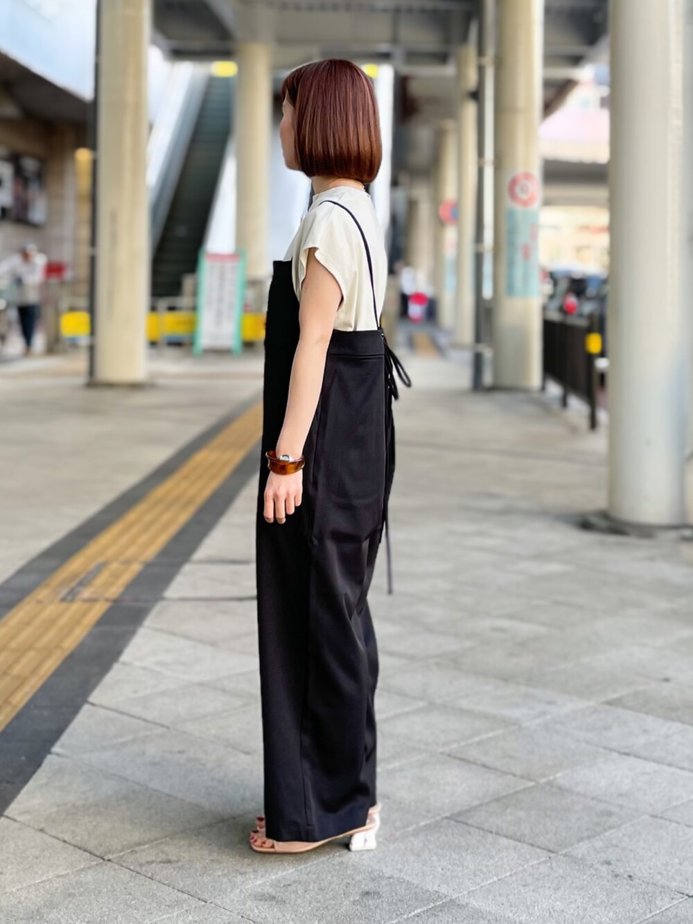 ブラック系のサロペット/オーバーオール、グレー系のTシャツ/カットソー、ベージュ系のサンダルを着用したレディースの春コーディネートの3枚目の写真