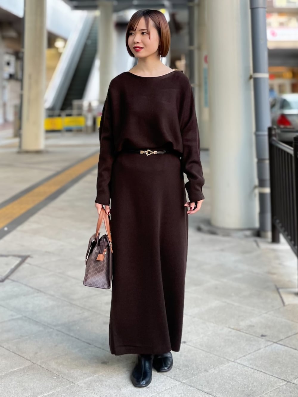 ベージュ系のチェスターコート、ブラウン系のニット/セーター、ブラウン系のスカートを着用したレディースの冬コーディネートの3枚目の写真