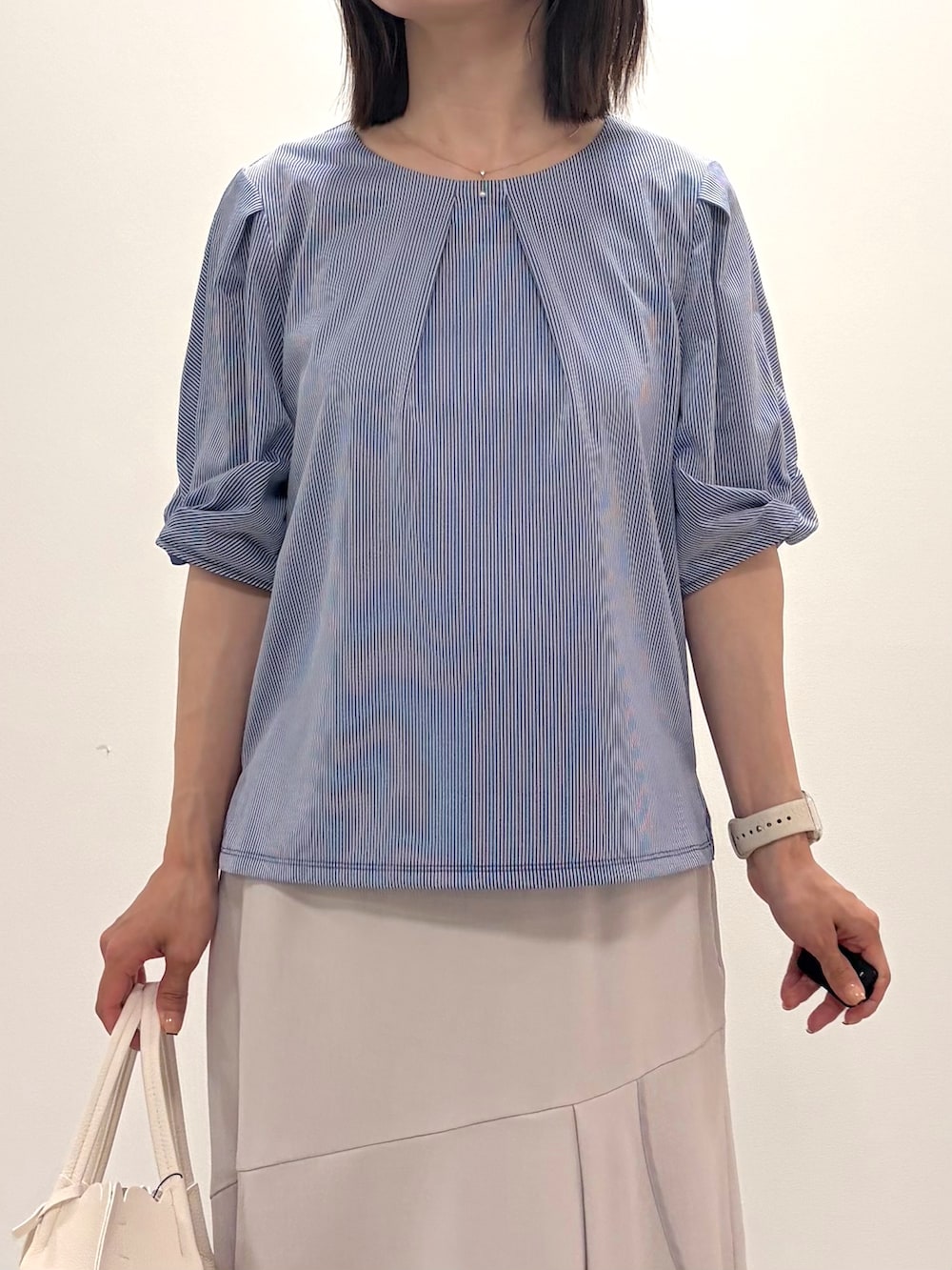 ブルー系のTシャツ/カットソー、ベージュ系のスカート、ホワイト系のトートバッグを着用したレディースの春コーディネートの7枚目の写真