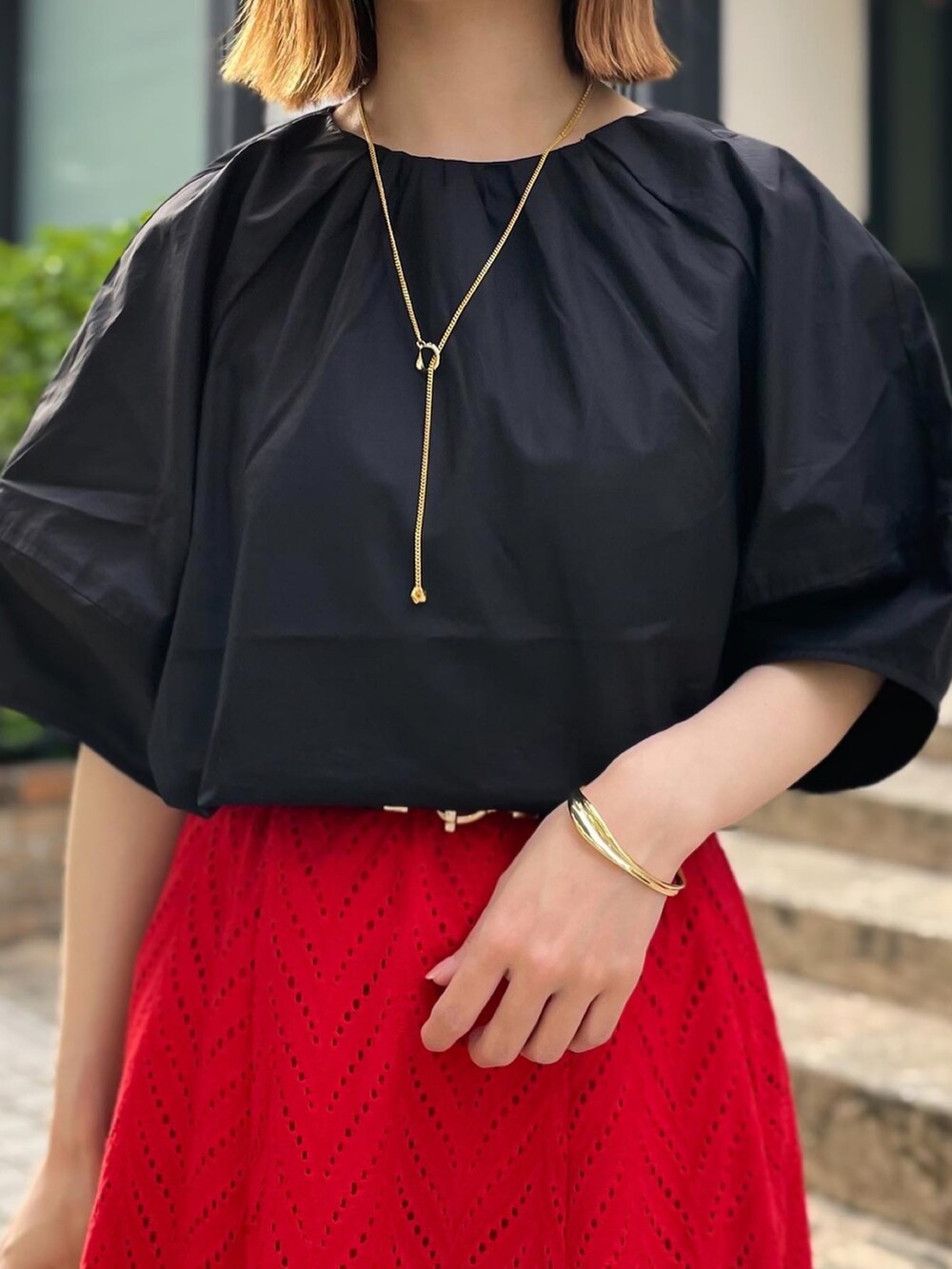 レッド系のスカート、ブラック系のシャツ/ブラウス、ブラック系のショルダーバッグを着用したレディースの夏コーディネートの3枚目の写真