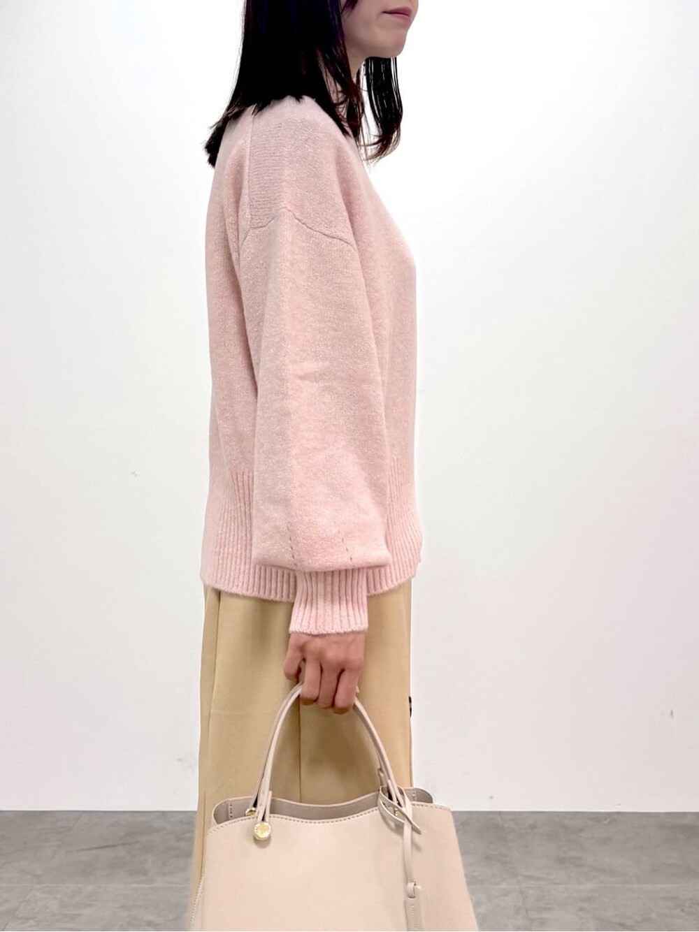 ピンク系のニット/セーター、ベージュ系のスカート、ベージュ系のボストンバッグを着用したレディースの冬コーディネートの4枚目の写真