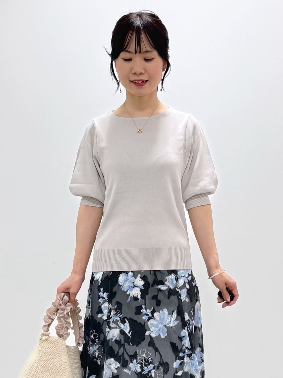 ベージュ系のニット/セーター、グレー系のスカート、ベージュ系のトートバッグを着用したレディースの春コーディネートの4枚目の写真