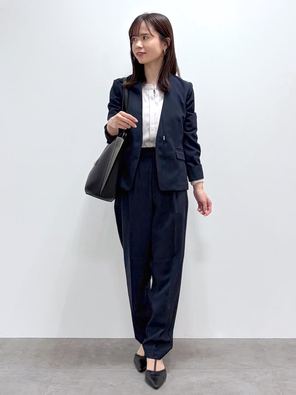 ブラック系のパンプス、ベージュ系のトートバッグ、ブルー系のスカートを着用したレディースの春コーディネートの8枚目の写真