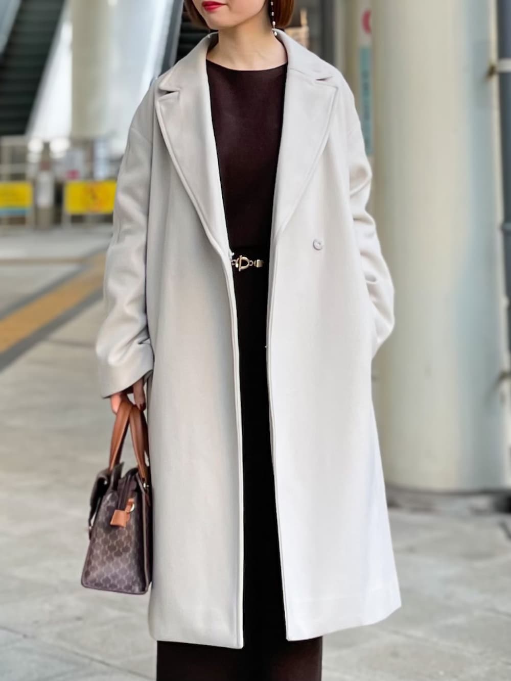 ベージュ系のチェスターコート、ブラウン系のニット/セーター、ブラウン系のスカートを着用したレディースの冬コーディネートの2枚目の写真