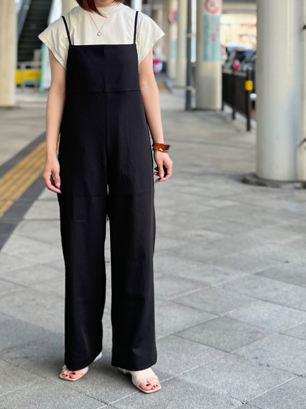 ブラック系のサロペット/オーバーオール、グレー系のTシャツ/カットソー、ベージュ系のサンダルを着用したレディースの春コーディネートの2枚目の写真