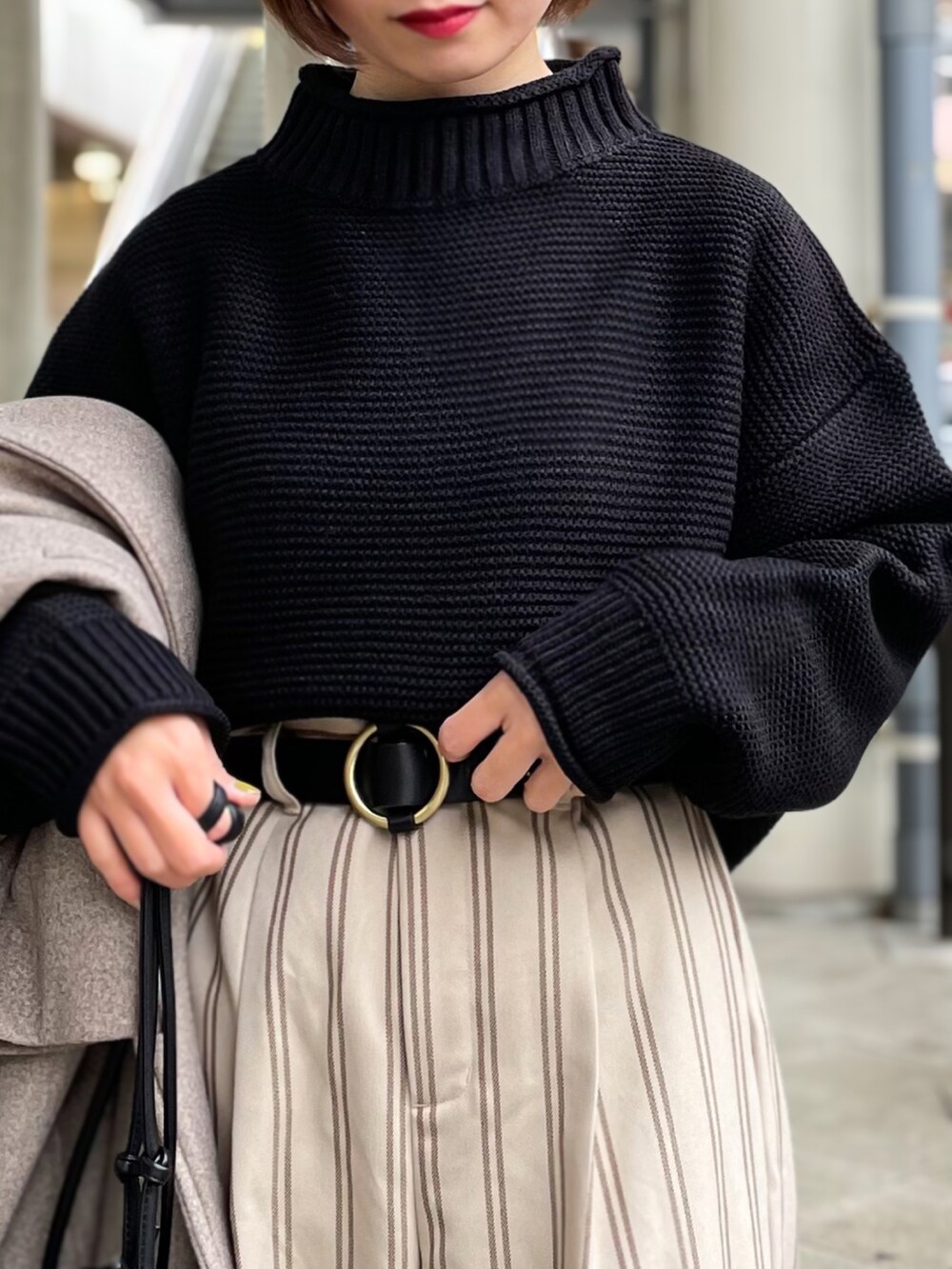 ブラック系のニット/セーター、ベージュ系のその他パンツ、ブラウン系のチェスターコートを着用したレディースの冬コーディネートの3枚目の写真
