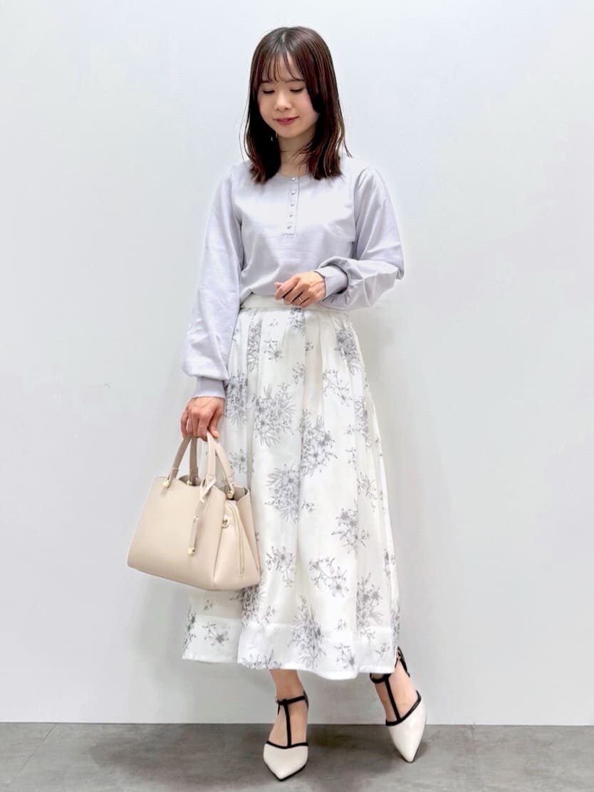 ブルー系のトレンチコート、ブルー系のニット/セーター、ベージュ系のスカートを着用したレディースの春コーディネートの2枚目の写真
