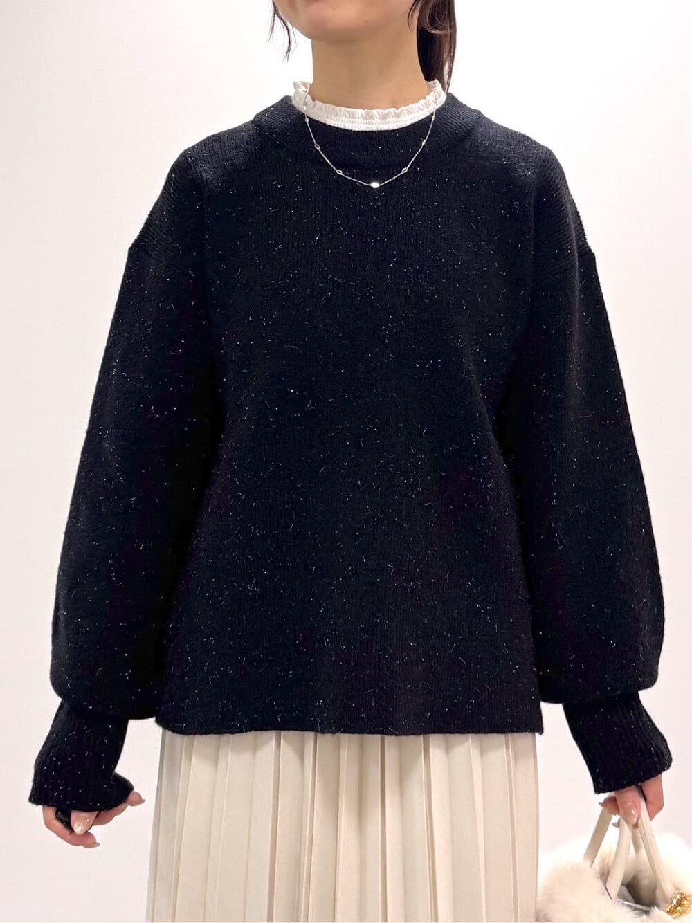 ブラック系のニット/セーター、ホワイト系のTシャツ/カットソー、ホワイト系のスカートを着用したレディースの冬コーディネートの2枚目の写真