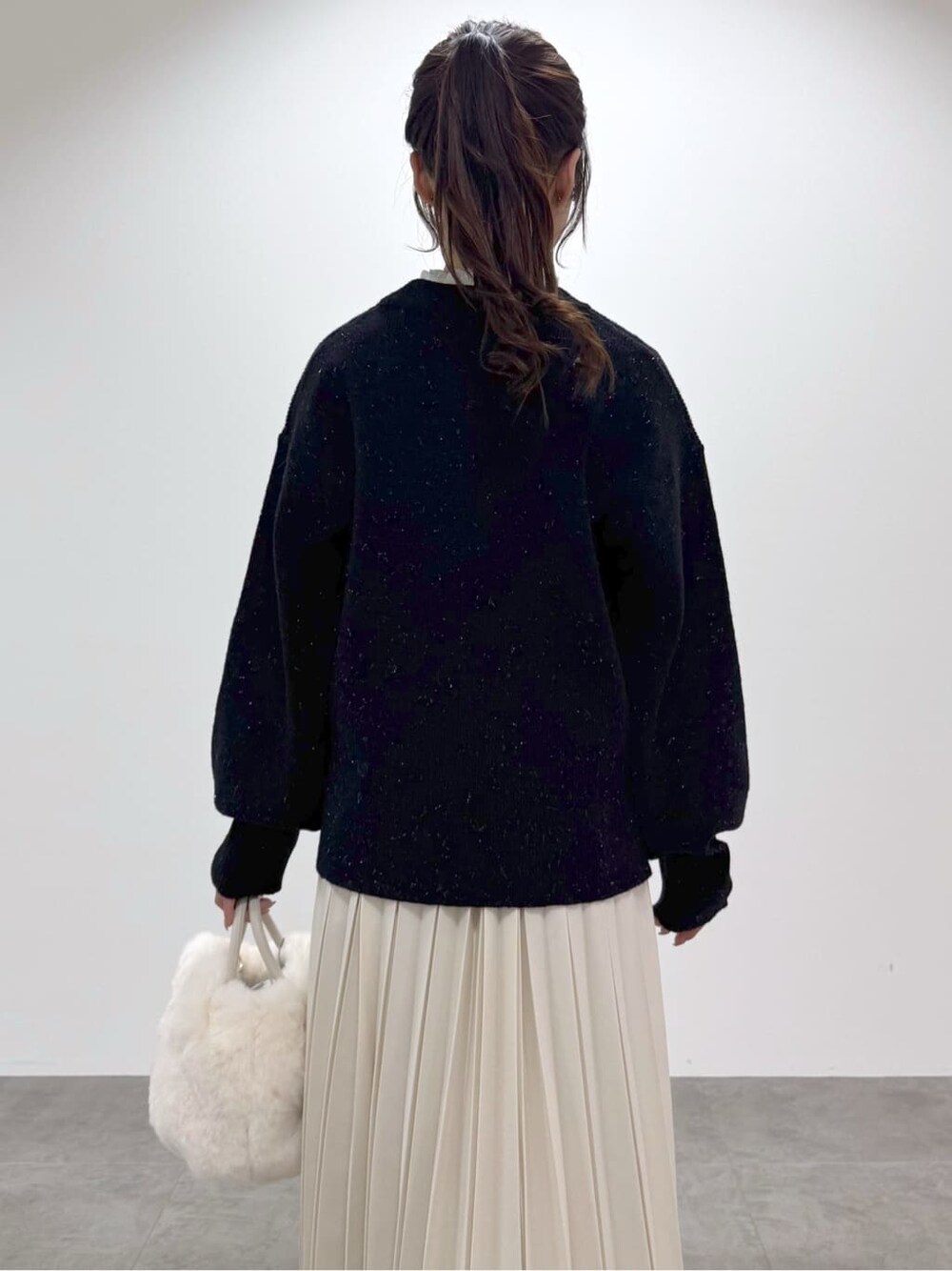 ブラック系のニット/セーター、ホワイト系のTシャツ/カットソー、ホワイト系のスカートを着用したレディースの冬コーディネートの3枚目の写真