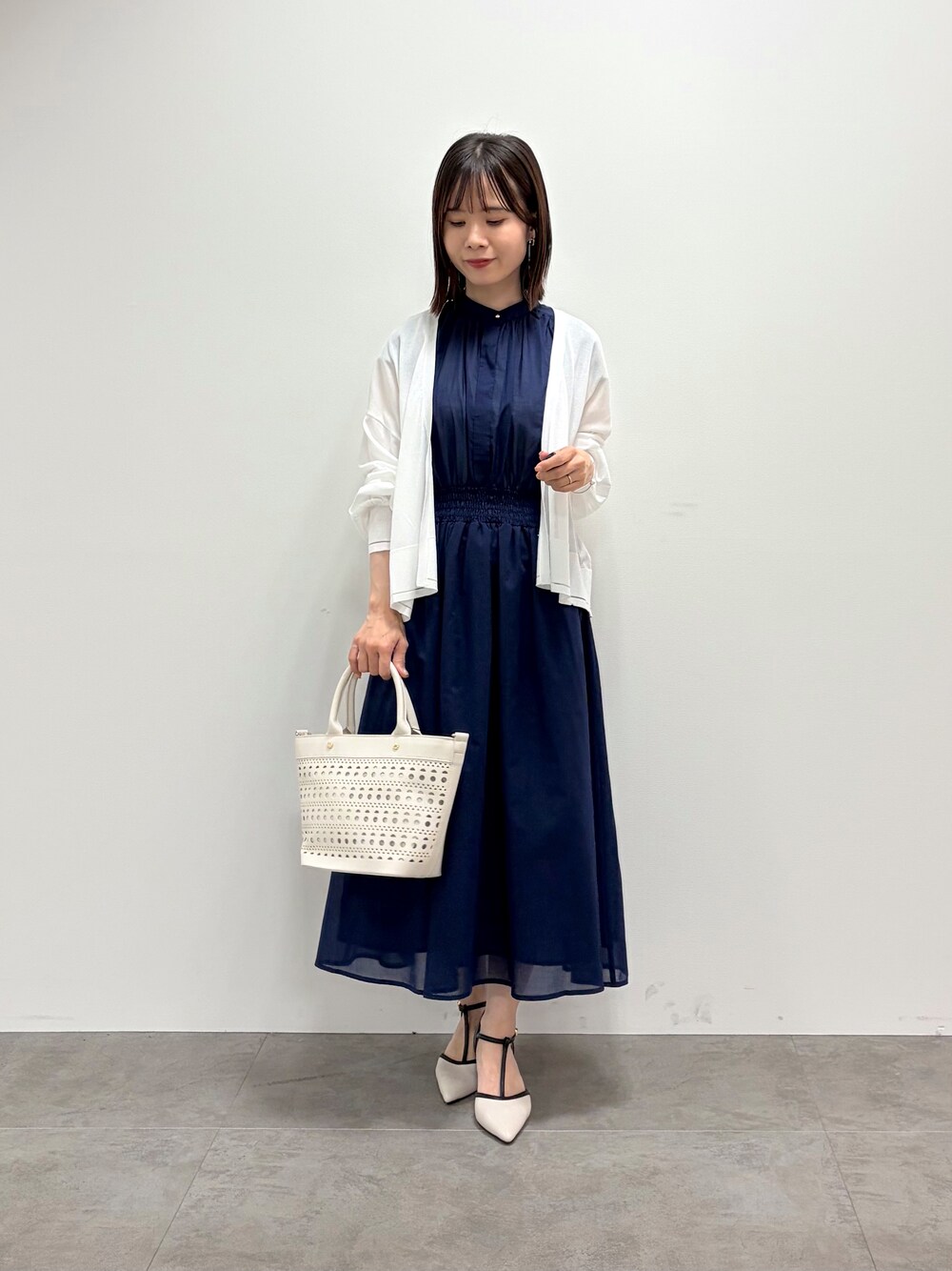 ブルー系のワンピース、ホワイト系のトートバッグ、ベージュ系のパンプスを着用したレディースの春コーディネートの3枚目の写真