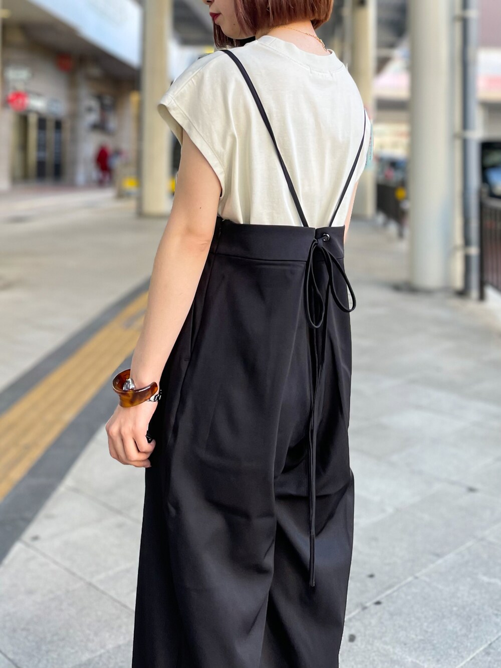 ブラック系のサロペット/オーバーオール、グレー系のTシャツ/カットソー、ベージュ系のサンダルを着用したレディースの春コーディネートの4枚目の写真