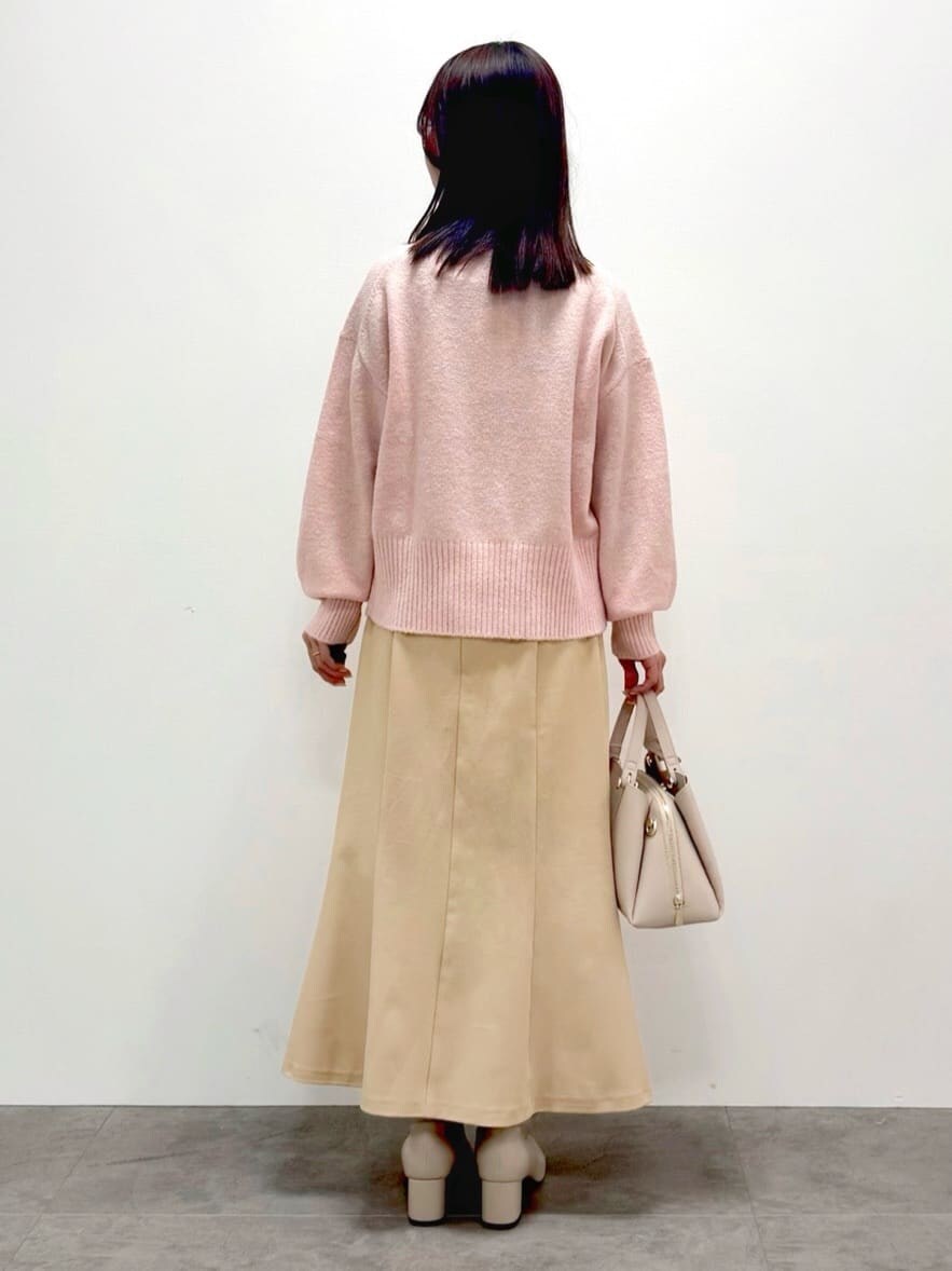 ピンク系のニット/セーター、ベージュ系のスカート、ベージュ系のボストンバッグを着用したレディースの冬コーディネートの3枚目の写真