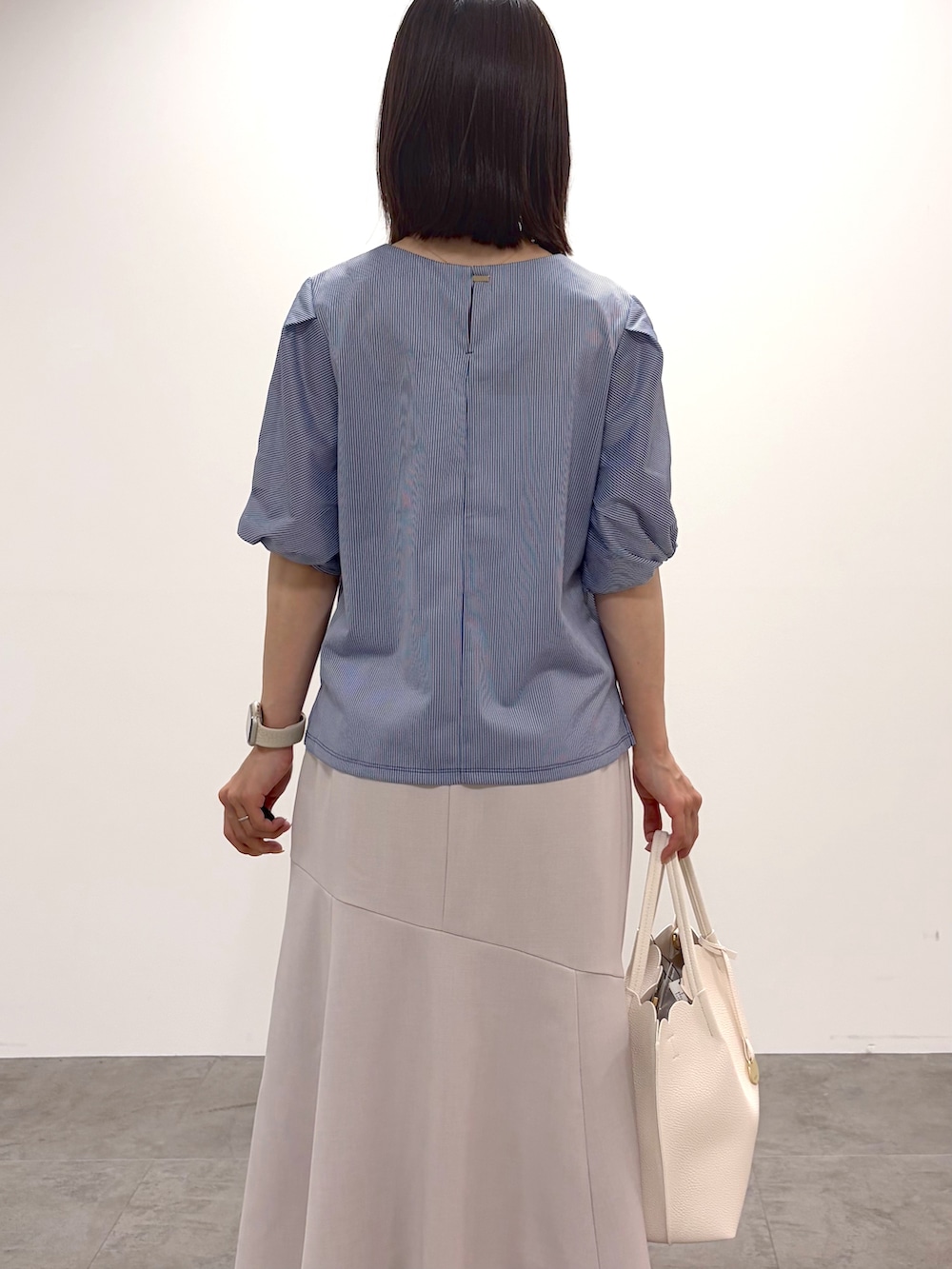 ブルー系のTシャツ/カットソー、ベージュ系のスカート、ホワイト系のトートバッグを着用したレディースの春コーディネートの8枚目の写真