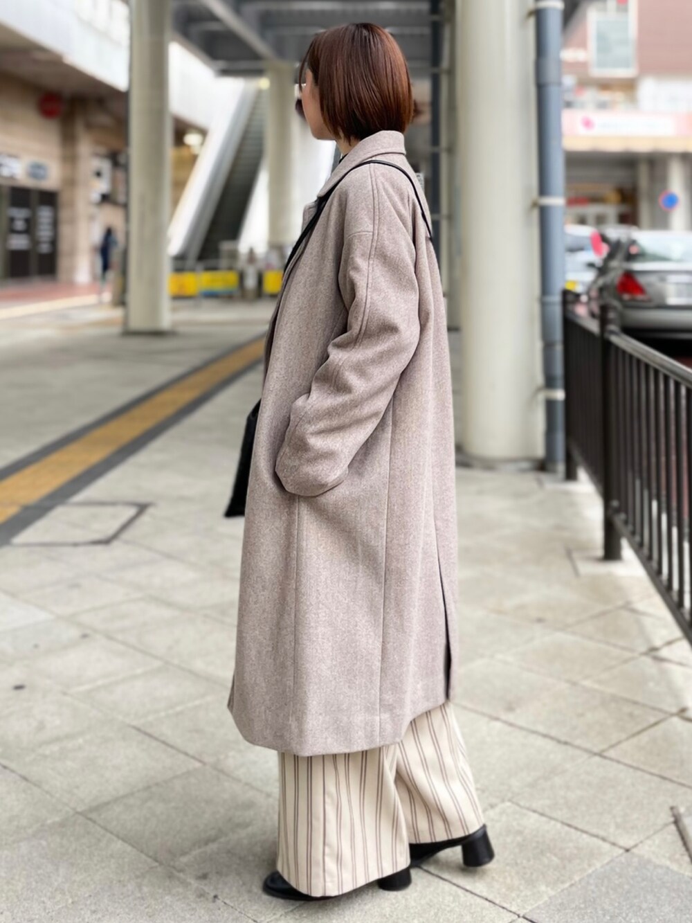 ブラック系のニット/セーター、ベージュ系のその他パンツ、ブラウン系のチェスターコートを着用したレディースの冬コーディネートの2枚目の写真