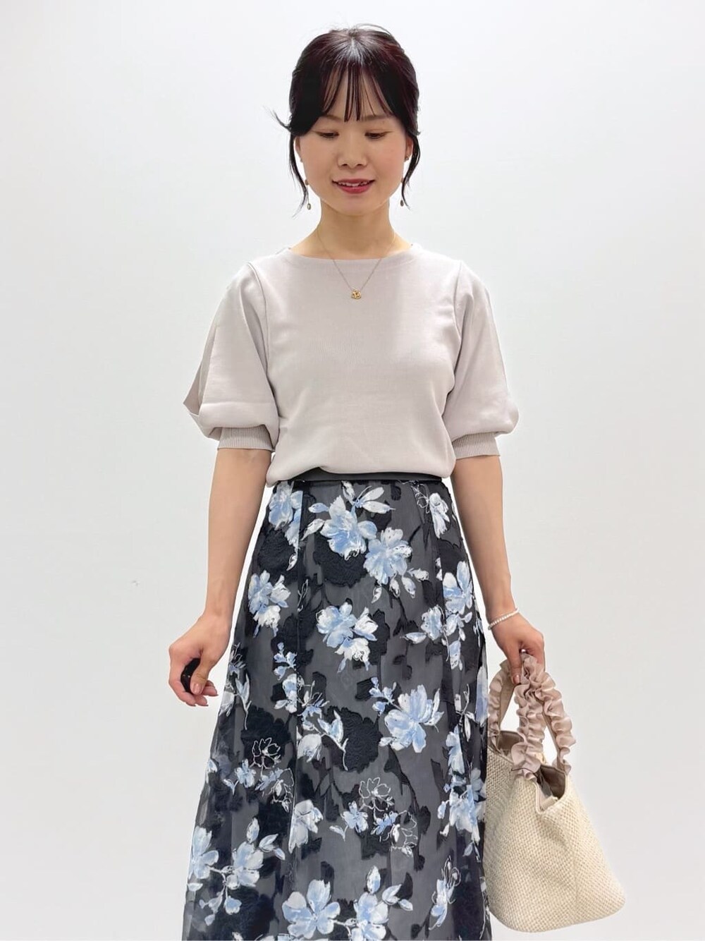 ベージュ系のニット/セーター、グレー系のスカート、ベージュ系のトートバッグを着用したレディースの春コーディネートの2枚目の写真