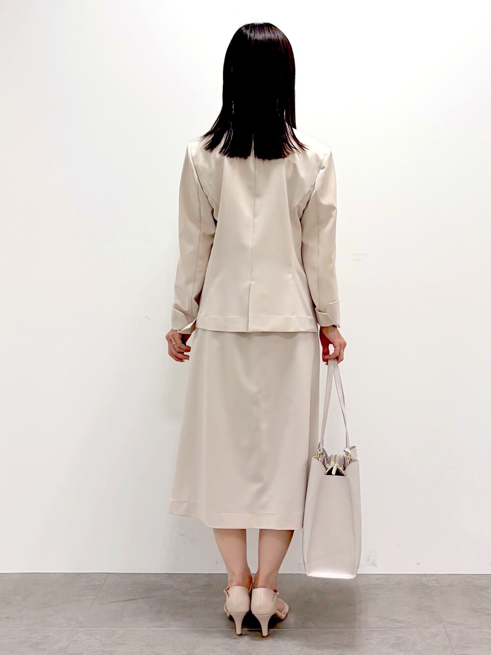 ベージュ系のノーカラージャケット、ホワイト系のシャツ/ブラウス、ベージュ系のスカートを着用したレディースの春コーディネートの6枚目の写真
