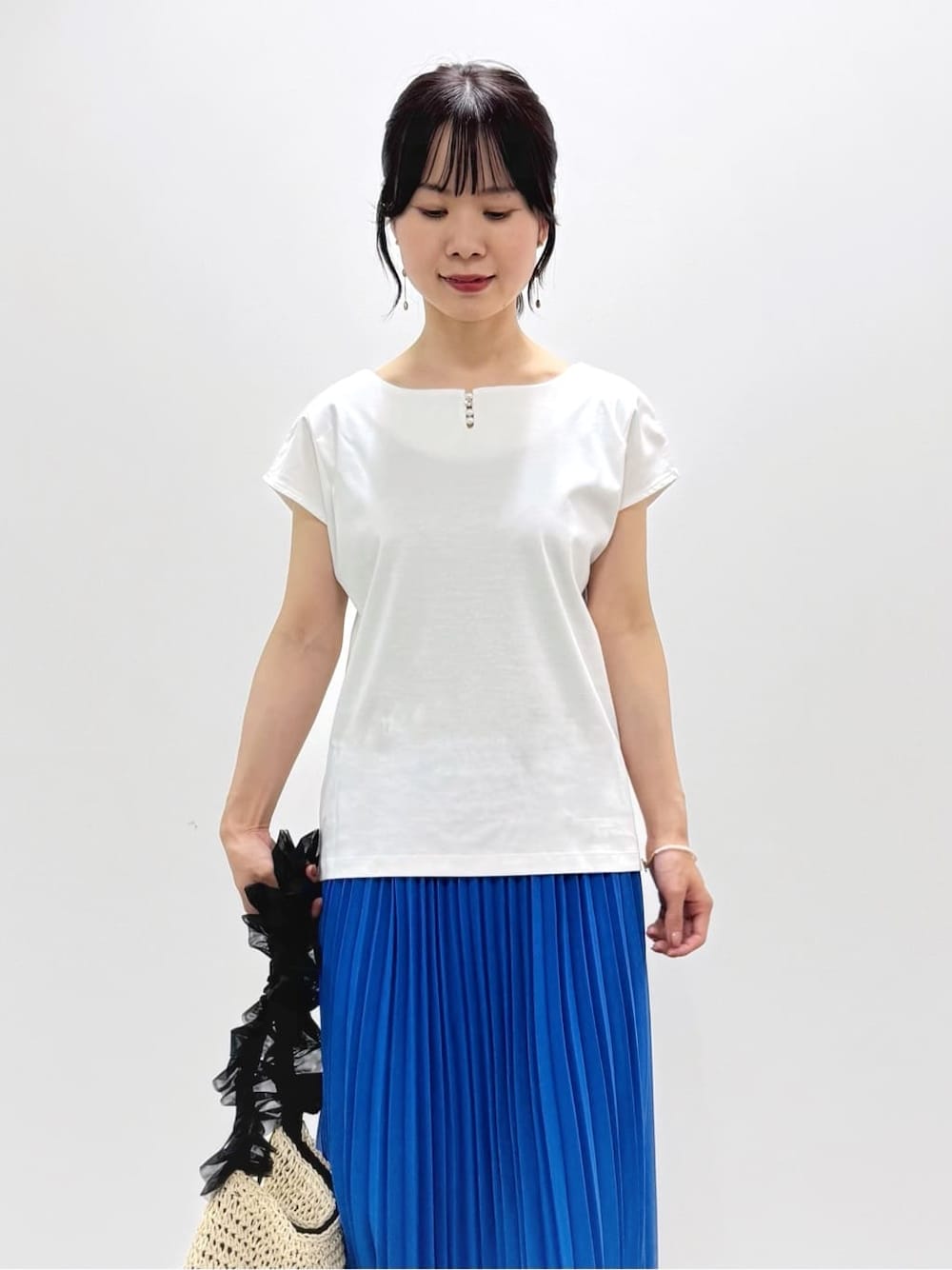 ホワイト系のTシャツ/カットソー、ブルー系のスカート、ベージュ系のトートバッグを着用したレディースの春コーディネートの5枚目の写真