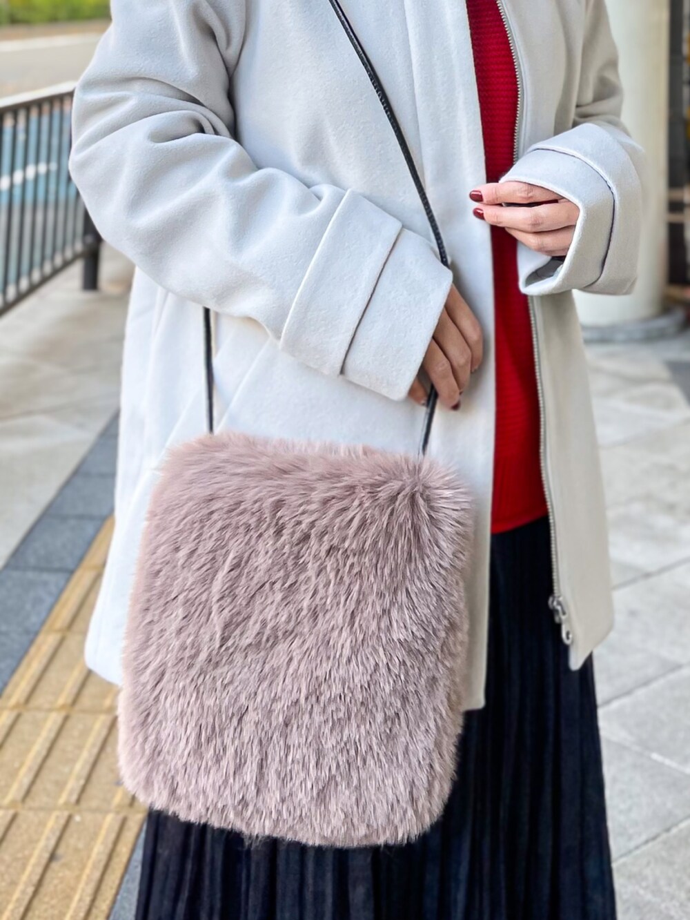 ベージュ系のその他アウター、レッド系のニット/セーター、ブルー系のスカートを着用したレディースの冬コーディネートの5枚目の写真