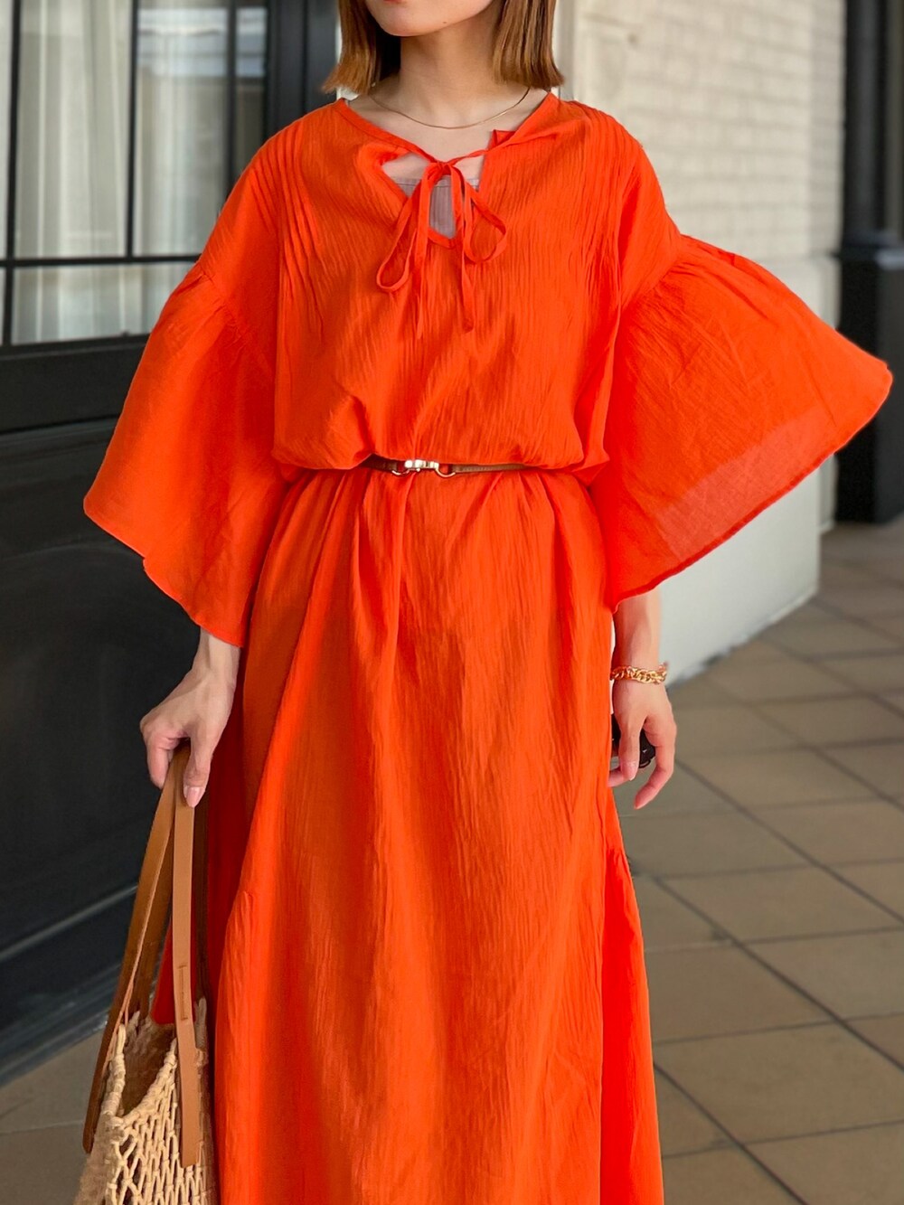 オレンジ系のワンピース、イエロー系のトートバッグを着用したレディースの夏コーディネートの5枚目の写真