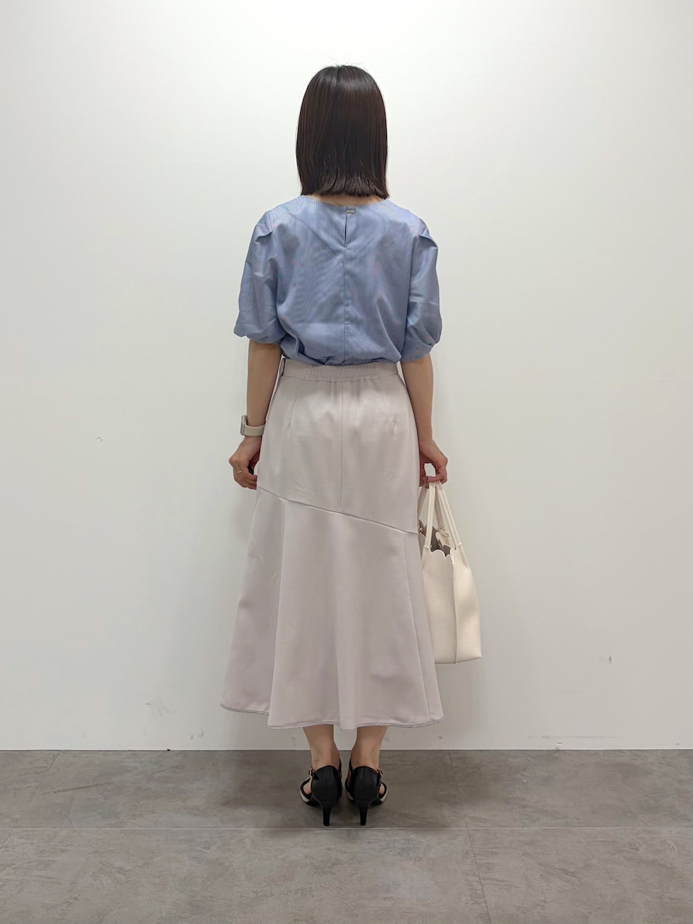 ブルー系のTシャツ/カットソー、ベージュ系のスカート、ホワイト系のトートバッグを着用したレディースの春コーディネートの3枚目の写真