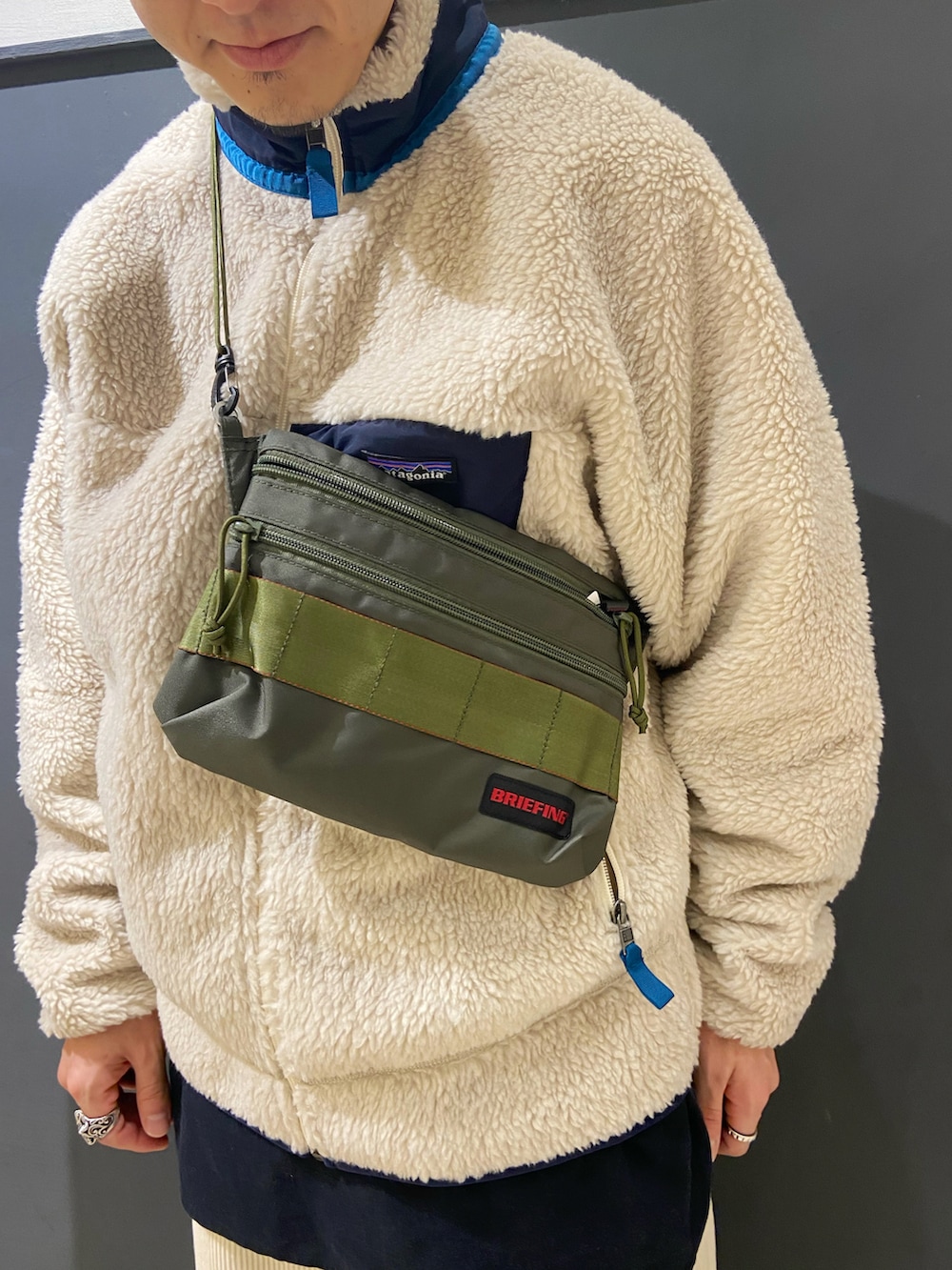 ホワイト系のブルゾン、ブルー系のモカシン/デッキシューズ、ホワイト系のパンツを着用したメンズの秋コーディネートの4枚目の写真