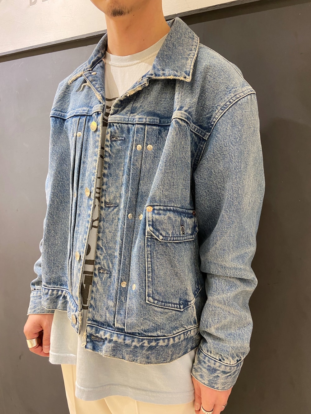 ブルー系のデニムジャケット、ホワイト系のパンツ、ブラック系のローファーを着用したメンズの秋コーディネートの2枚目の写真