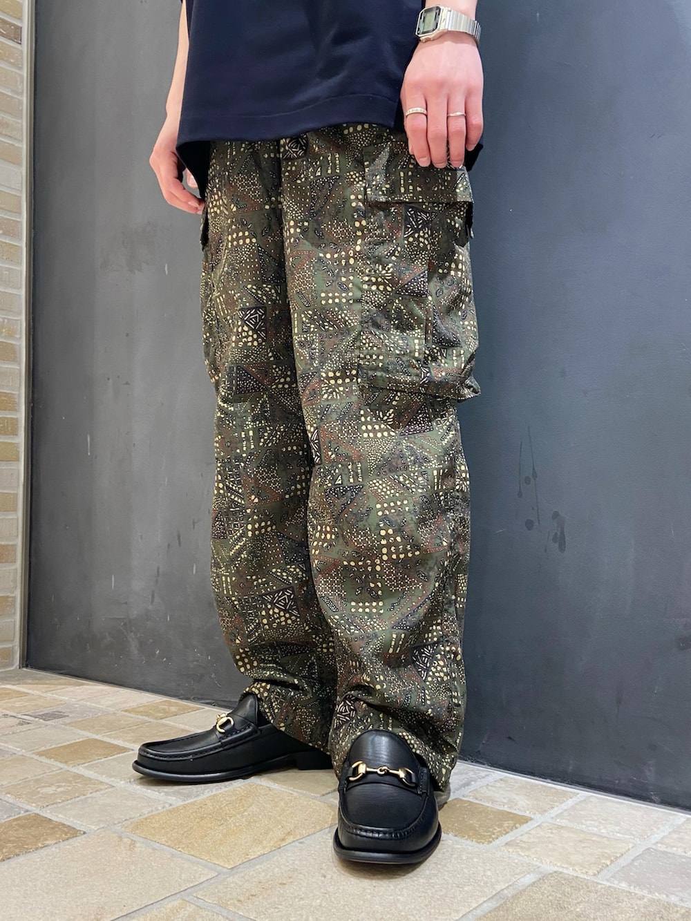 ブルー系のポロシャツ、グリーン系のカーゴパンツ、ブラック系のローファーを着用したメンズの夏コーディネートの4枚目の写真