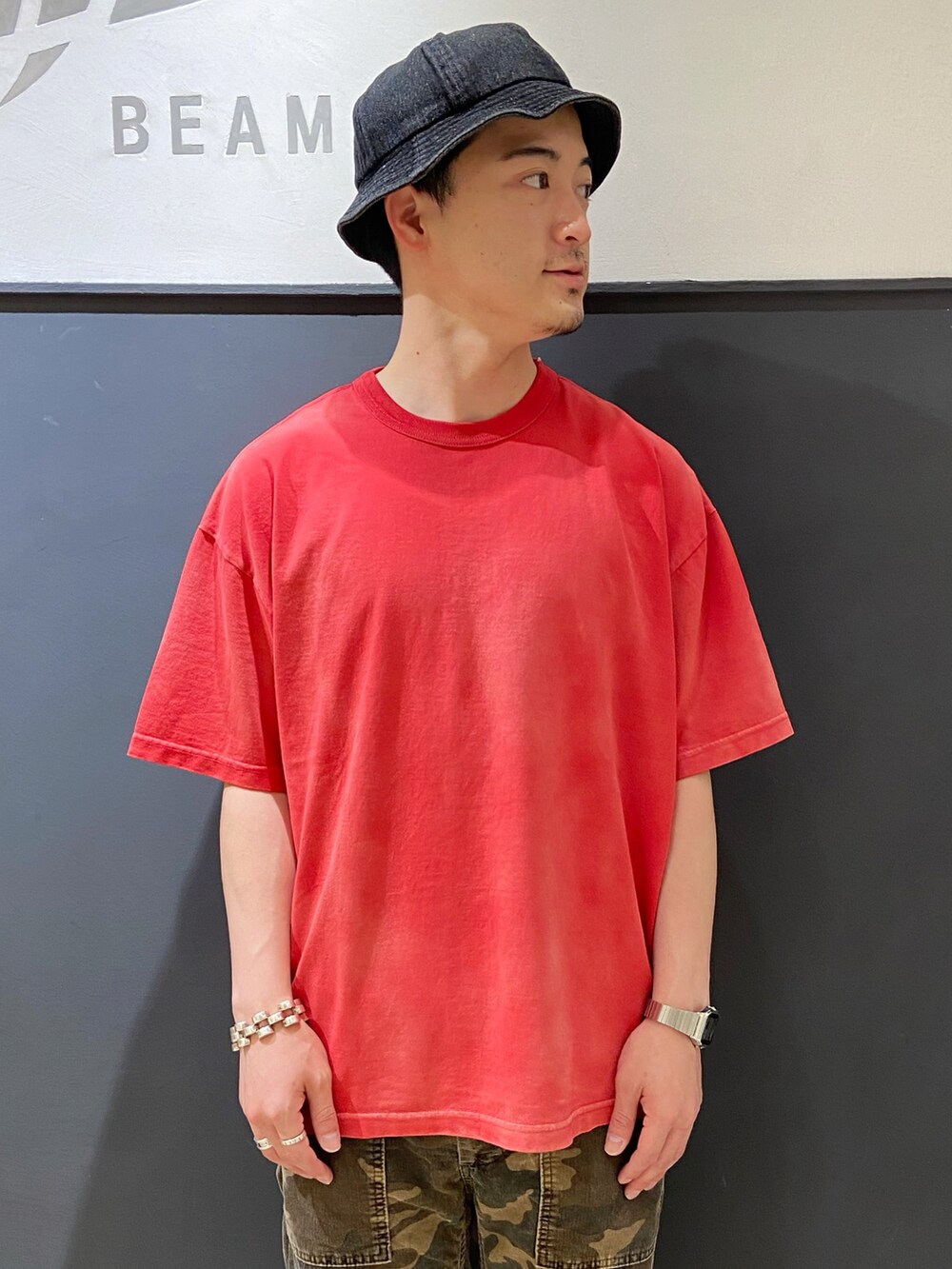 レッド系のTシャツ/カットソー、グリーン系のパンツ、ブラック系のスニーカーを着用したメンズの夏コーディネートの4枚目の写真