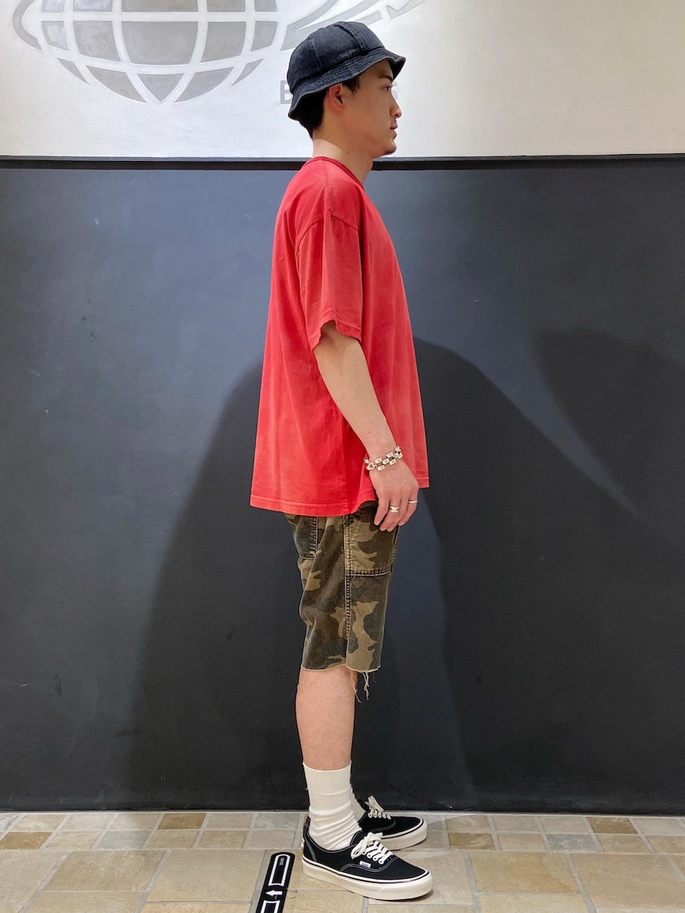レッド系のTシャツ/カットソー、グリーン系のパンツ、ブラック系のスニーカーを着用したメンズの夏コーディネートの2枚目の写真