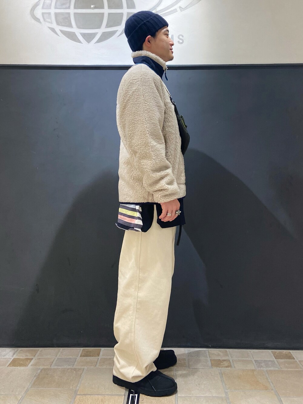 ホワイト系のブルゾン、ブルー系のモカシン/デッキシューズ、ホワイト系のパンツを着用したメンズの秋コーディネートの2枚目の写真