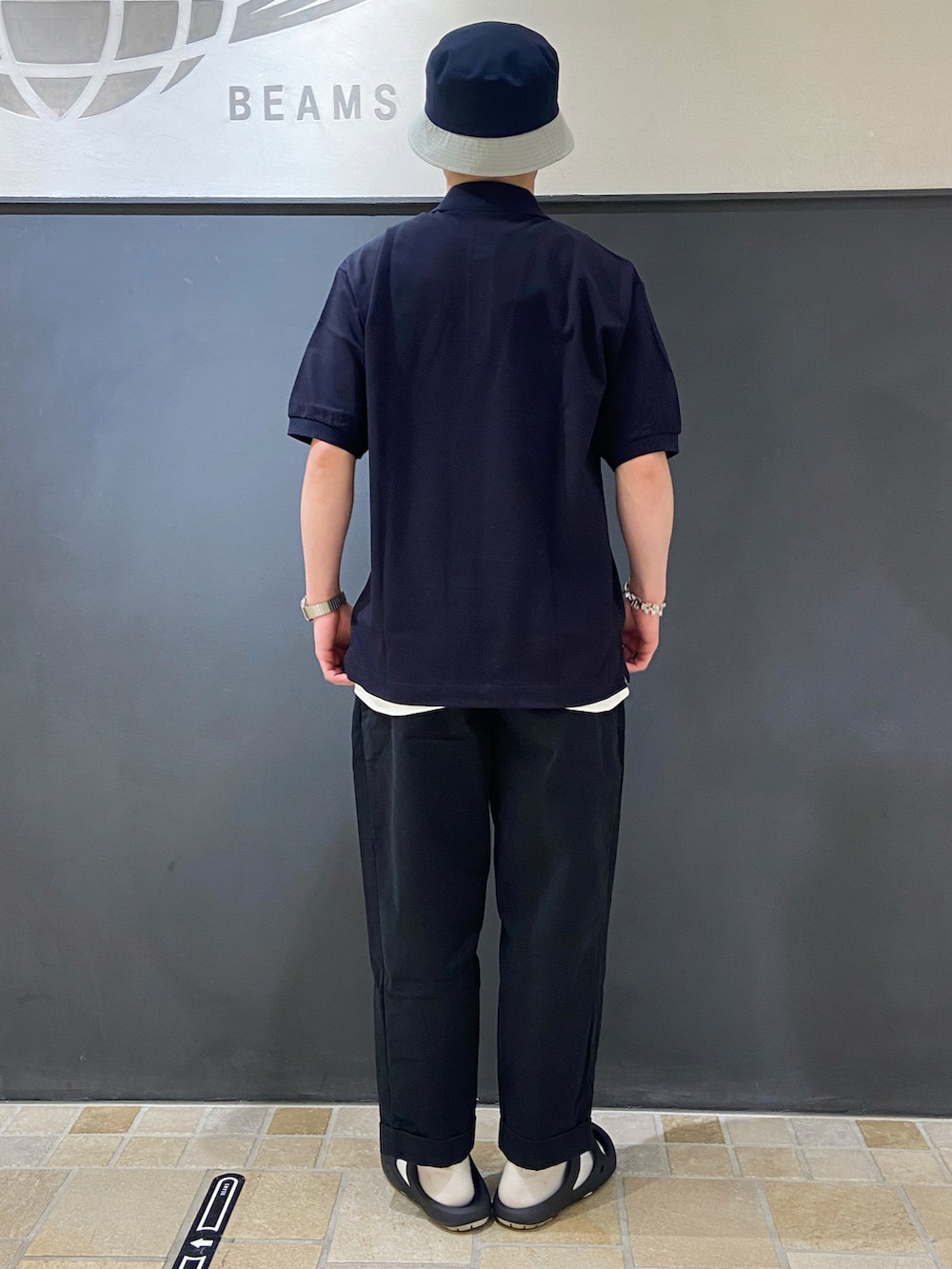 ブルー系のポロシャツ、ブルー系のチノパンツ、ブラック系のサンダルを着用したメンズの夏コーディネートの3枚目の写真