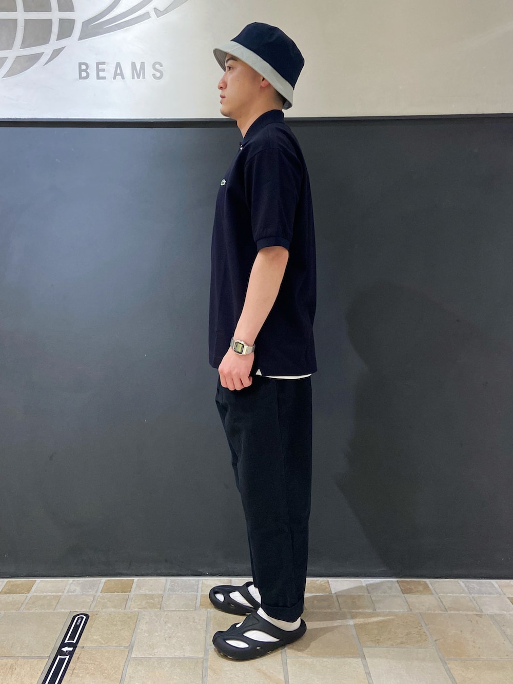 ブルー系のポロシャツ、ブルー系のチノパンツ、ブラック系のサンダルを着用したメンズの夏コーディネートの2枚目の写真