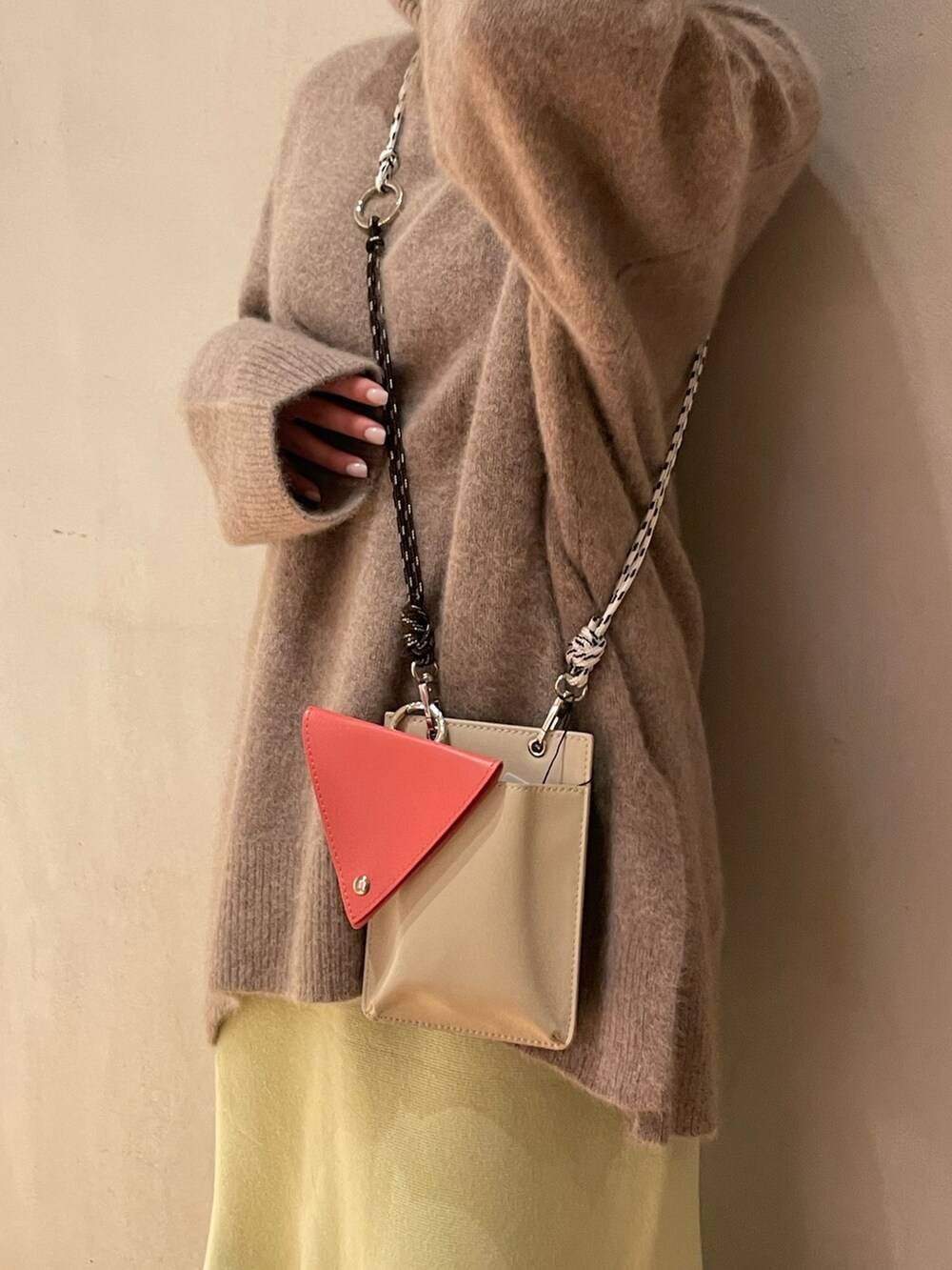 ベージュ系のショルダーバッグ、グリーン系のスカート、ブラック系のスニーカーを着用したレディースの秋コーディネートの3枚目の写真