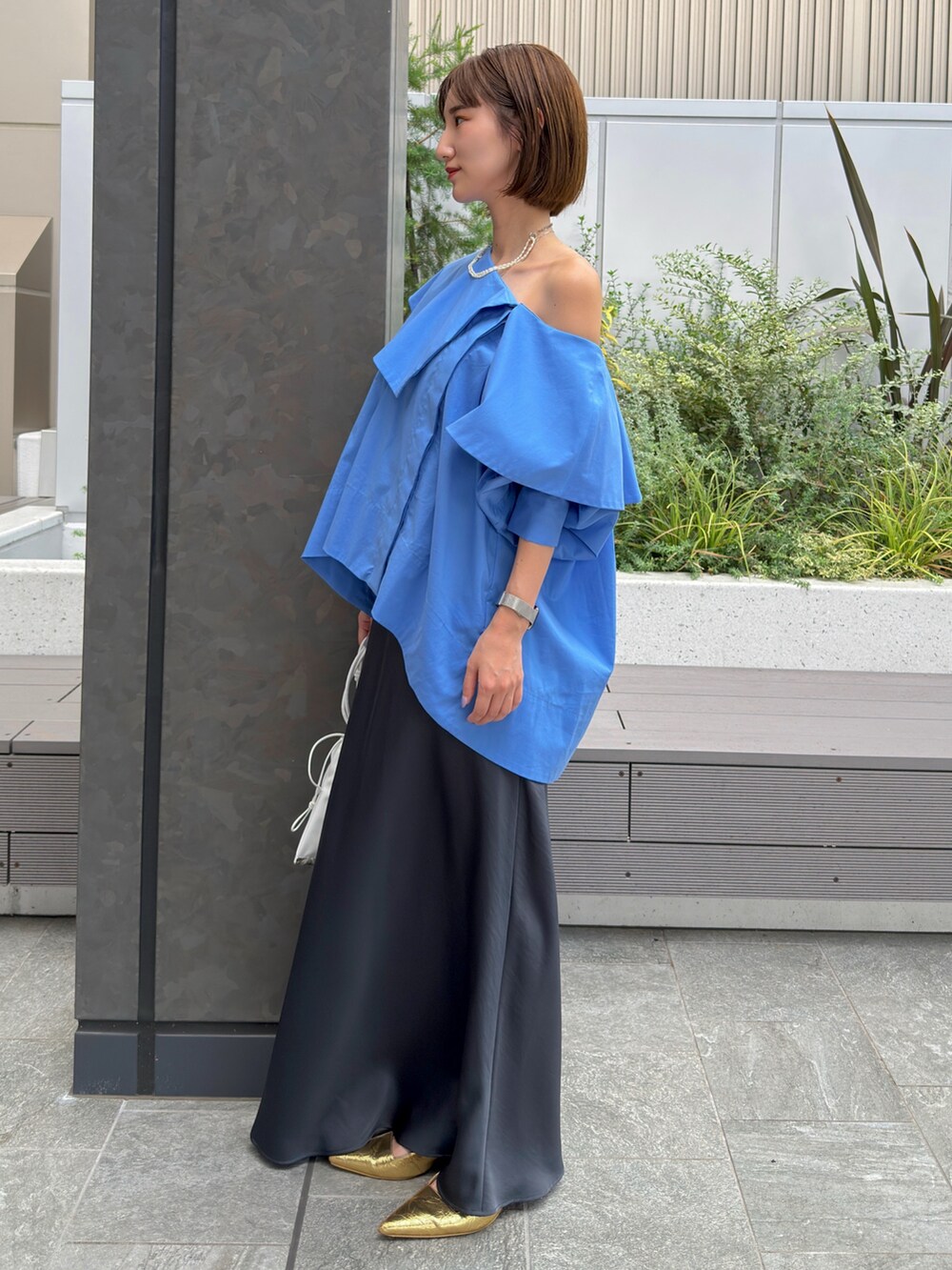 ブルー系のシャツ/ブラウス、グレー系のスカート、ゴールド系のネックレスを着用したレディースの夏コーディネートの2枚目の写真