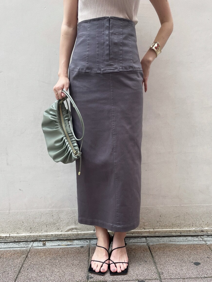 グリーン系のハンドバッグ、グレー系のスカート、ブラック系のサンダルを着用したレディースの春コーディネートの3枚目の写真