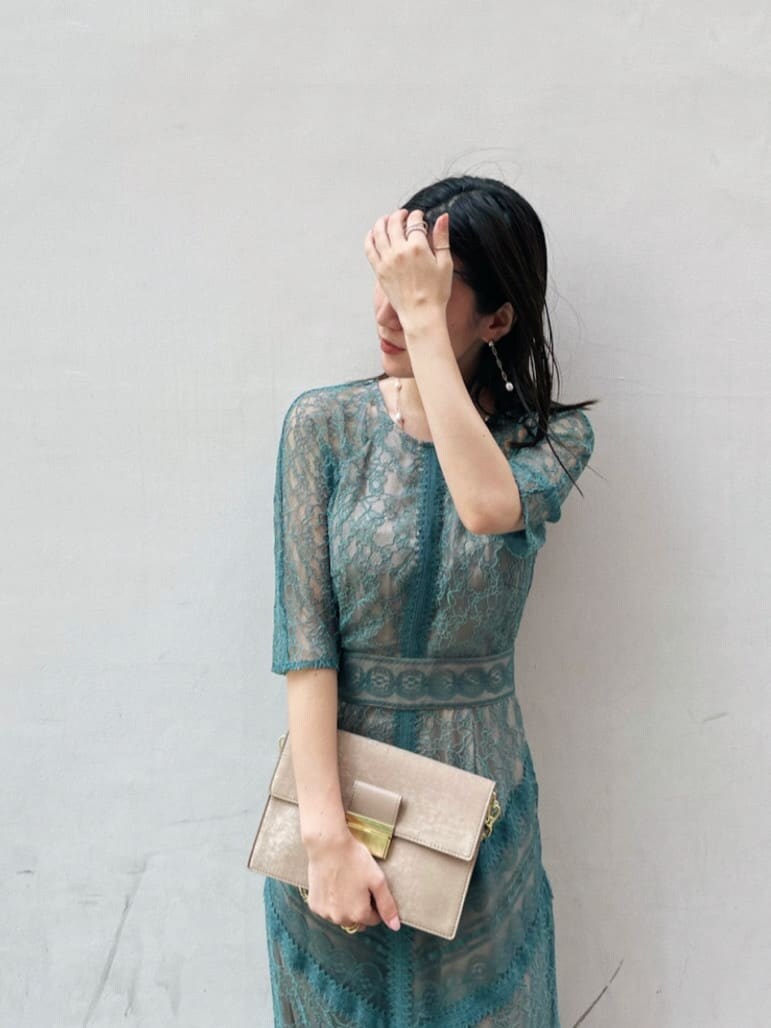 グリーン系のドレス、ベージュ系のパンプス、ブラウン系のクラッチバッグを着用したレディースの夏コーディネートの3枚目の写真