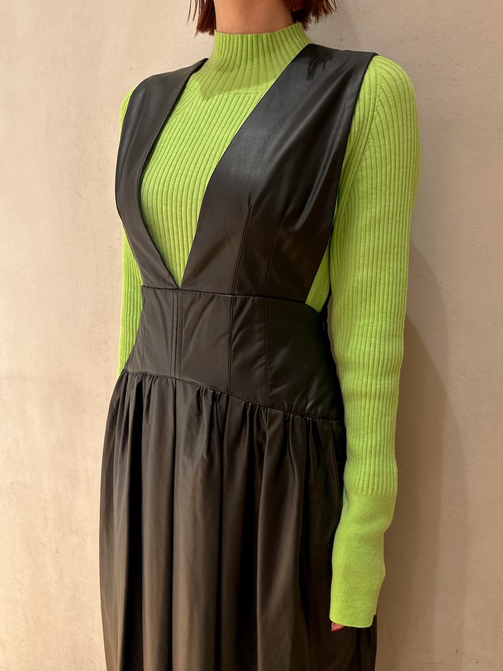 ブラック系のジャンパースカート、ブラック系のブーツ、グリーン系のニット/セーターを着用したレディースの秋コーディネートの4枚目の写真