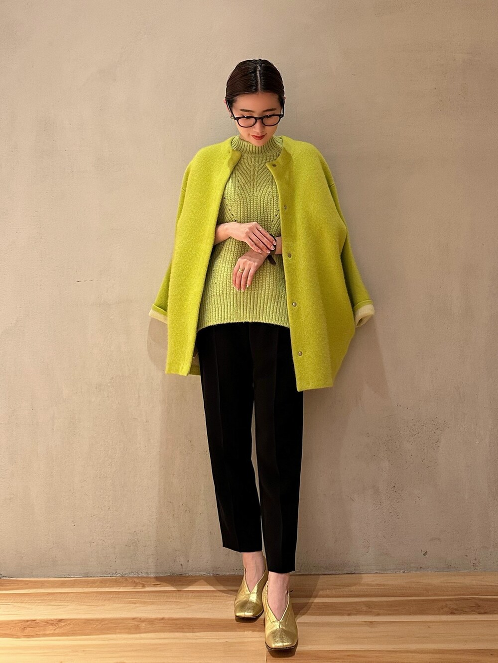 イエロー系のカーディガン/ボレロ、ブラック系のその他パンツ、グリーン系のニット/セーターを着用したレディースの冬コーディネートの2枚目の写真