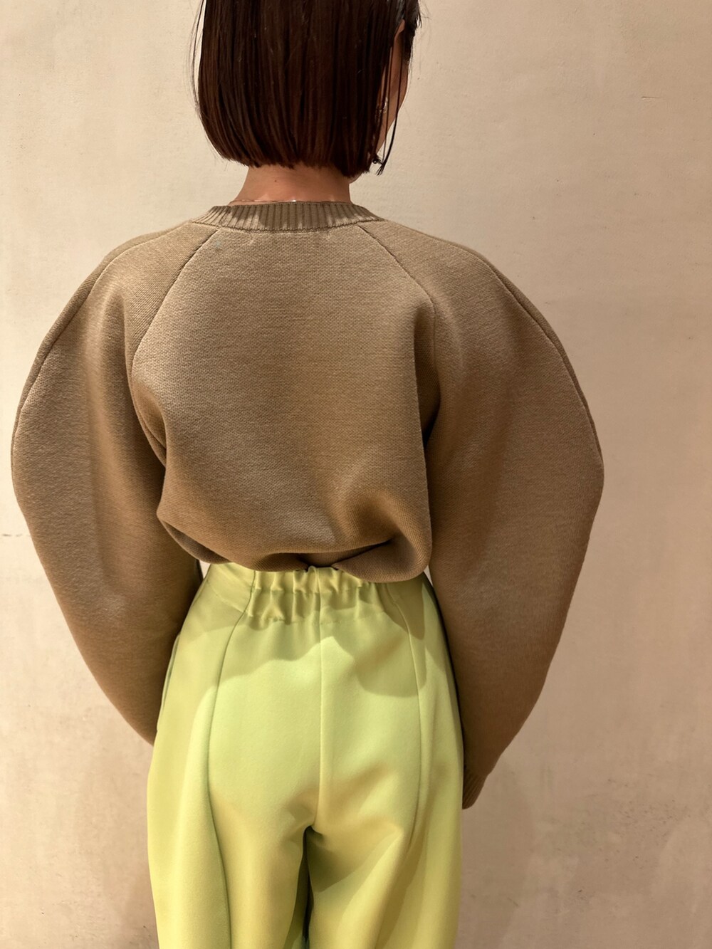 グリーン系のその他パンツ、ベージュ系のニット/セーター、ブラック系のブーティを着用したレディースの冬コーディネートの7枚目の写真