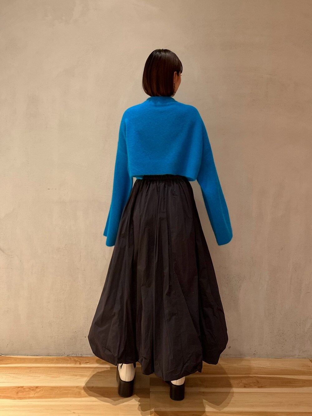 ブラック系のスカート、ブルー系のニット/セーター、ホワイト系のブーツを着用したレディースの冬コーディネートの4枚目の写真