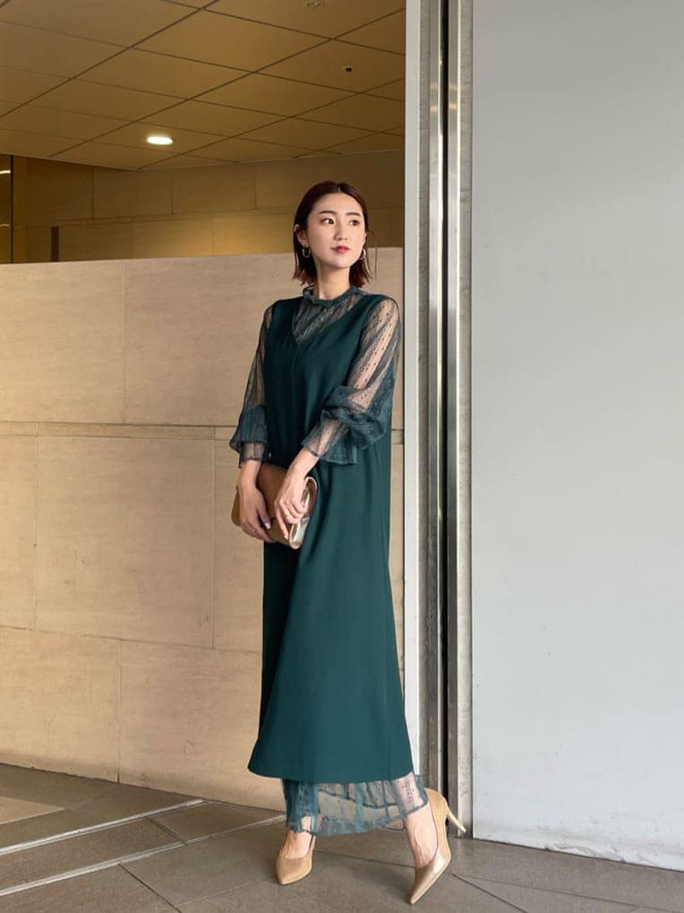 ゴールド系のパンプス、ゴールド系のクラッチバッグ、グリーン系のドレスを着用したレディースの夏コーディネートの2枚目の写真
