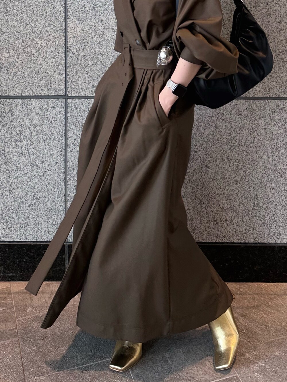 ブラウン系のワンピース、ゴールド系のブーツ、ブラック系のハンドバッグを着用したレディースの秋コーディネートの8枚目の写真