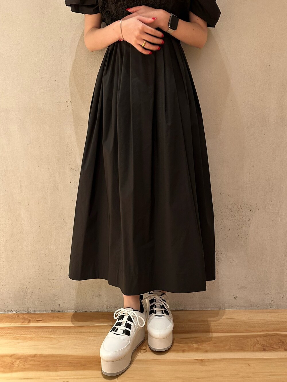 ブラック系のワンピース、ホワイト系のスニーカー、ゴールド系のピアス（両耳用）を着用したレディースの夏コーディネートの4枚目の写真