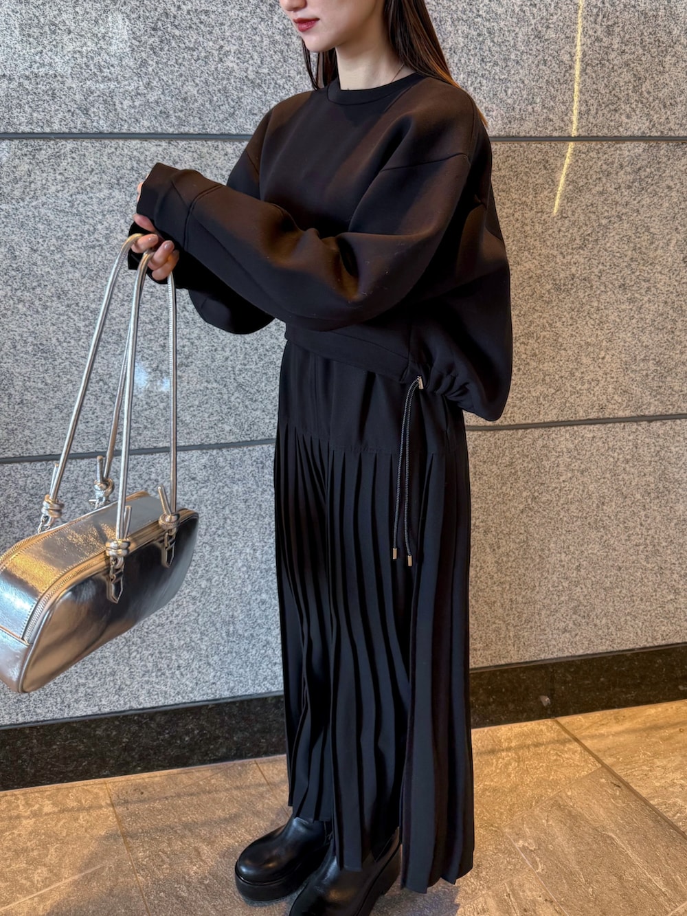 ブラック系のスウェット、シルバー系のボストンバッグ、ブラック系のワンピースを着用したレディースの冬コーディネートの3枚目の写真