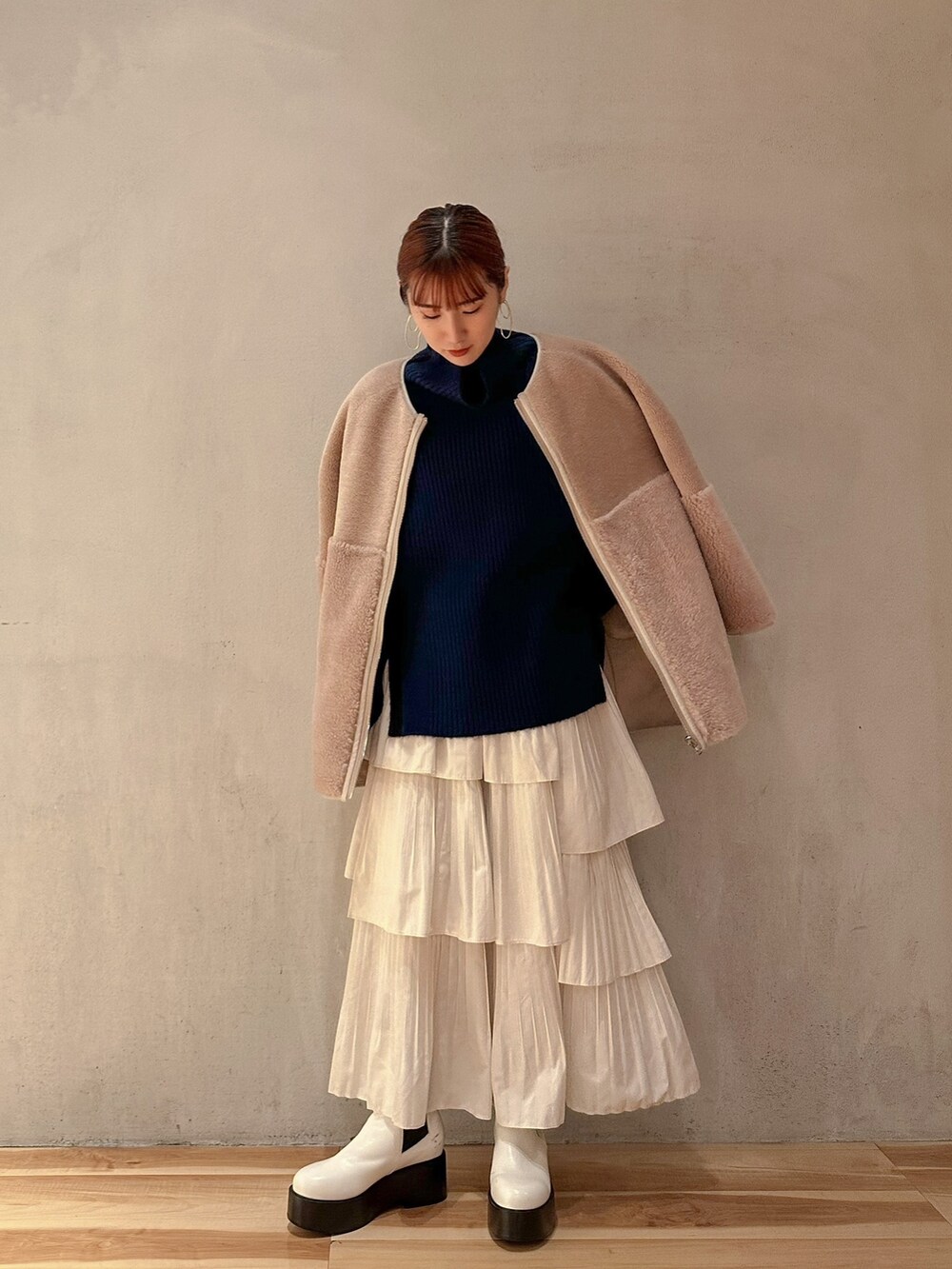 ホワイト系のスカート、ブルー系のニット/セーター、ベージュ系のノーカラーコートを着用したレディースの秋コーディネートの4枚目の写真