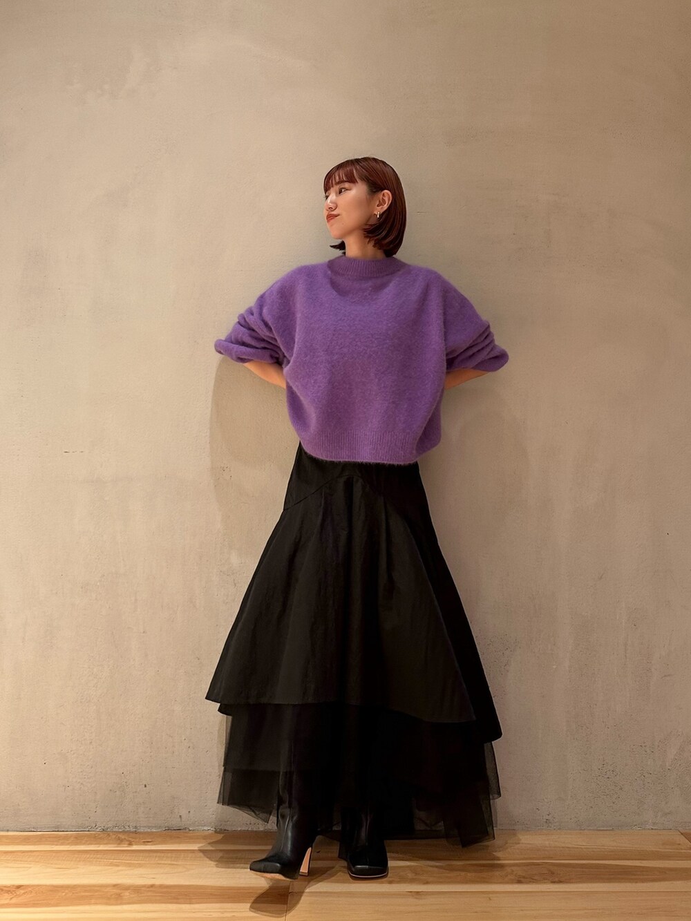 ブラック系のスカート、パープル系のニット/セーター、ブラック系のブーツを着用したレディースの秋コーディネートの4枚目の写真