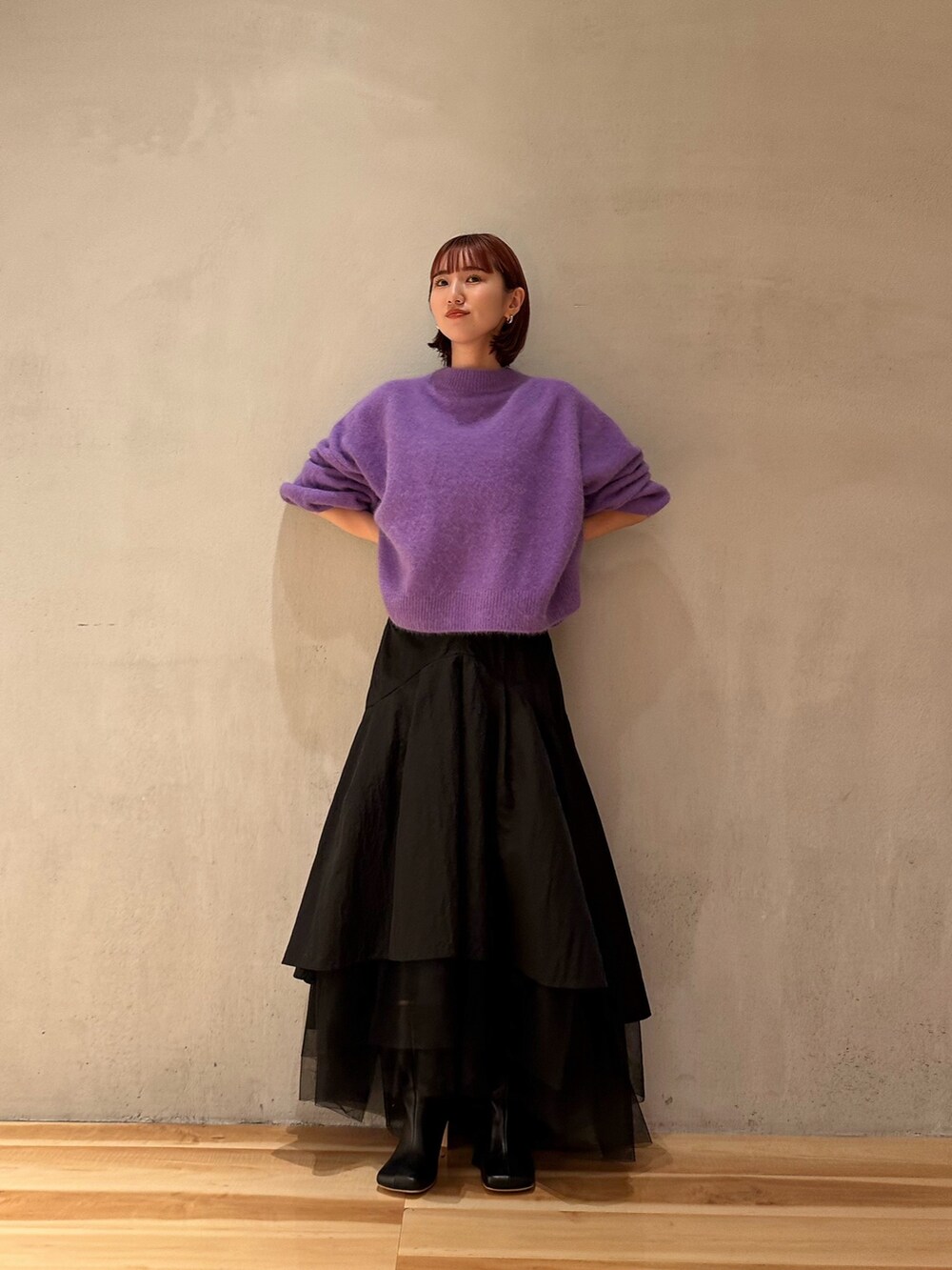 ブラック系のスカート、パープル系のニット/セーター、ブラック系のブーツを着用したレディースの秋コーディネートの3枚目の写真
