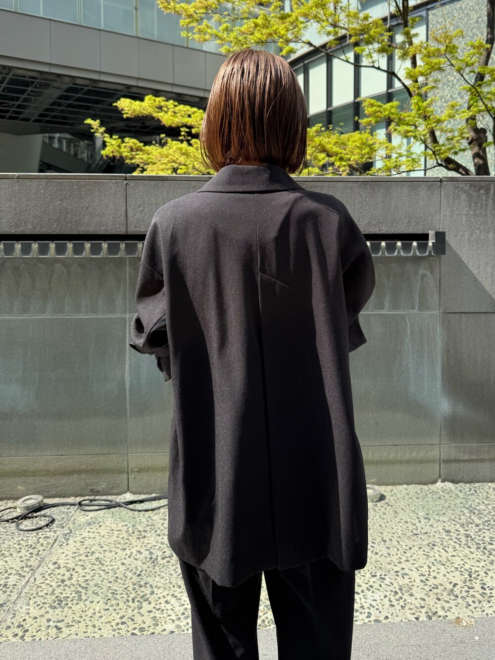 ブラック系のテーラードジャケット、ブラック系のその他パンツ、ゴールド系のサンダルを着用したレディースの春コーディネートの6枚目の写真